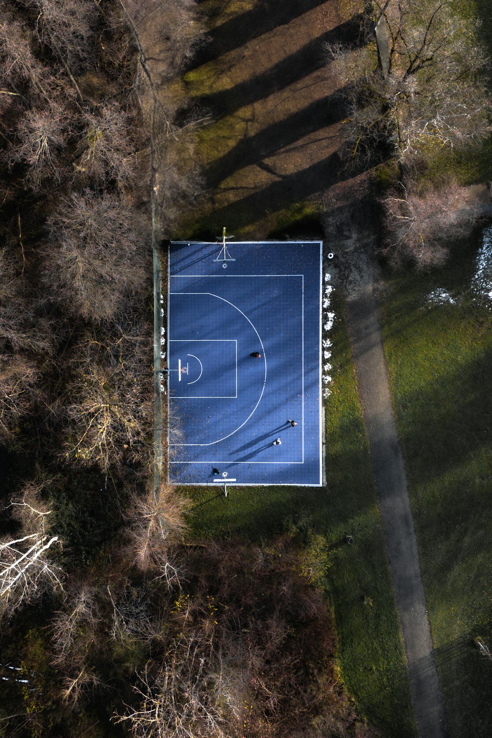 Drone shot of a basketball court surrounded by trees in Graz, Austria.