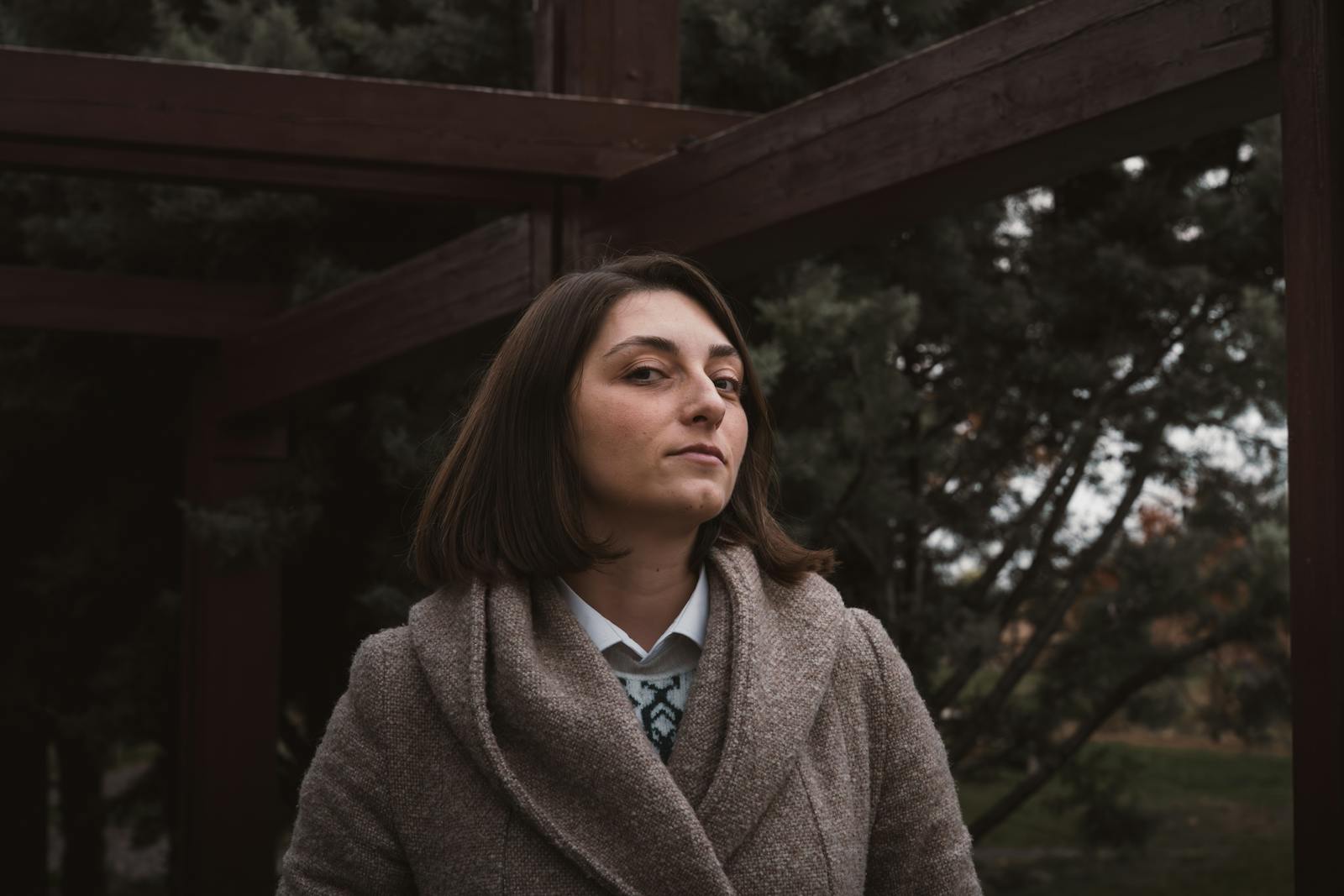 Woman in fall attire posing outdoors in Ankara, Turkey, with a serene expression.