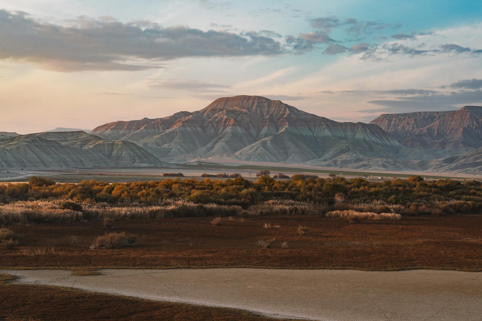 Breathtaking view of rolling mountains under a vibrant evening sky, capturing autumn's serene wilderness.