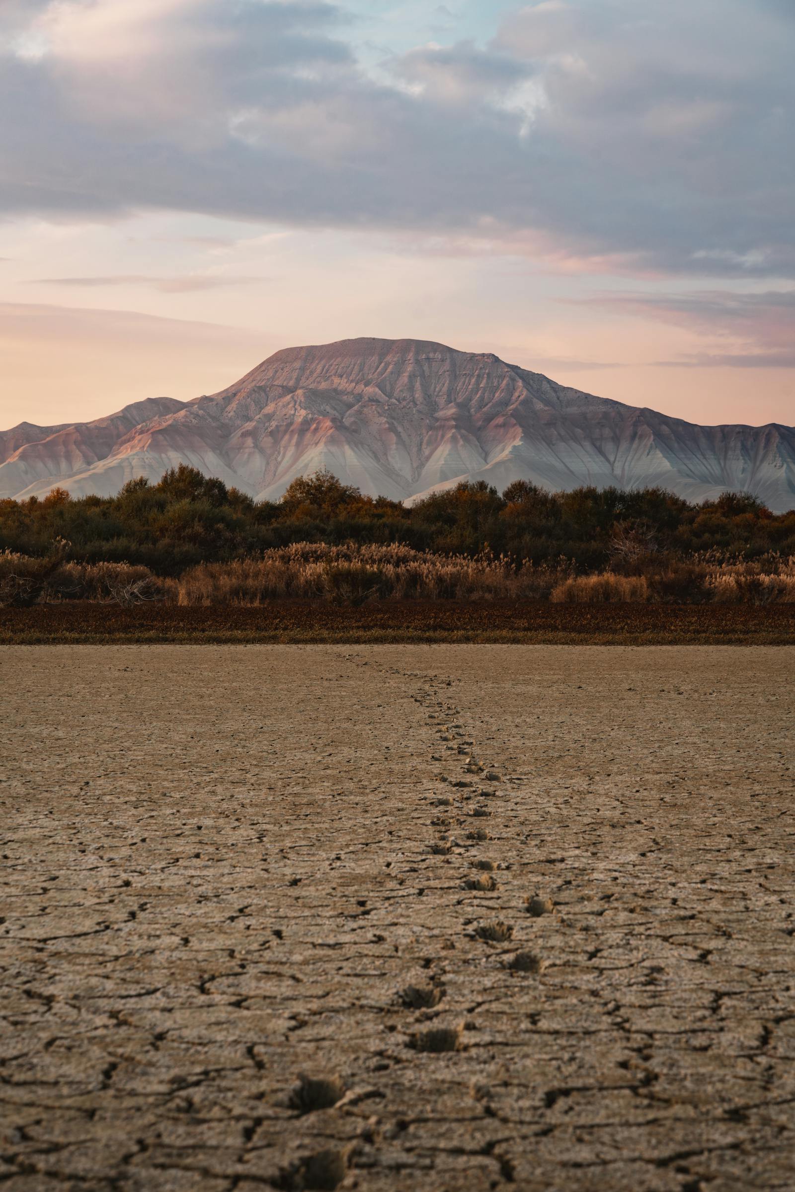 Cracked earth with footprints leading to a mountain under a pastel sky in Ankara, Turkey.