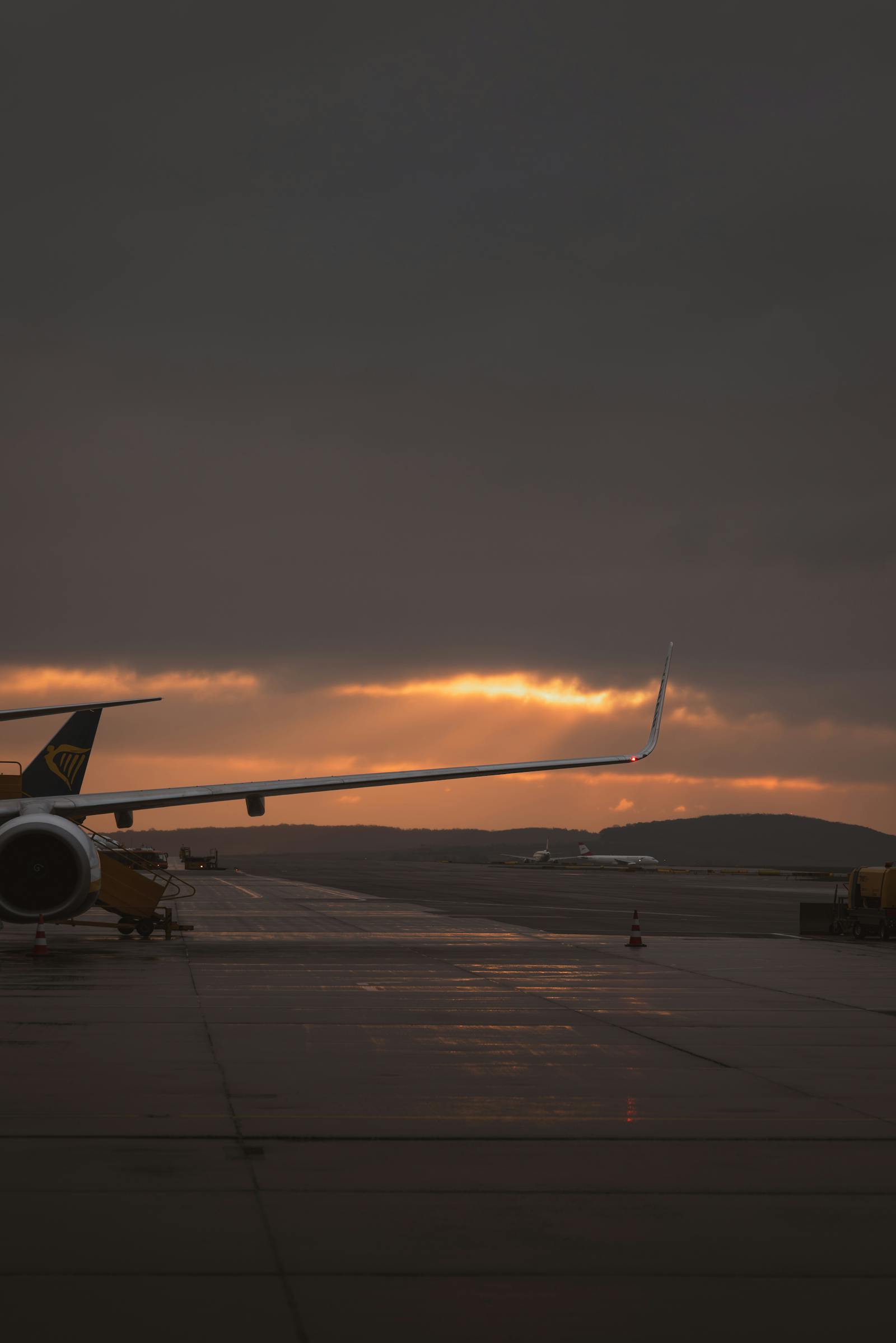 A scenic view of an airplane wing silhouetted against a beautiful sunset sky at Ankara airport, Türkiye.