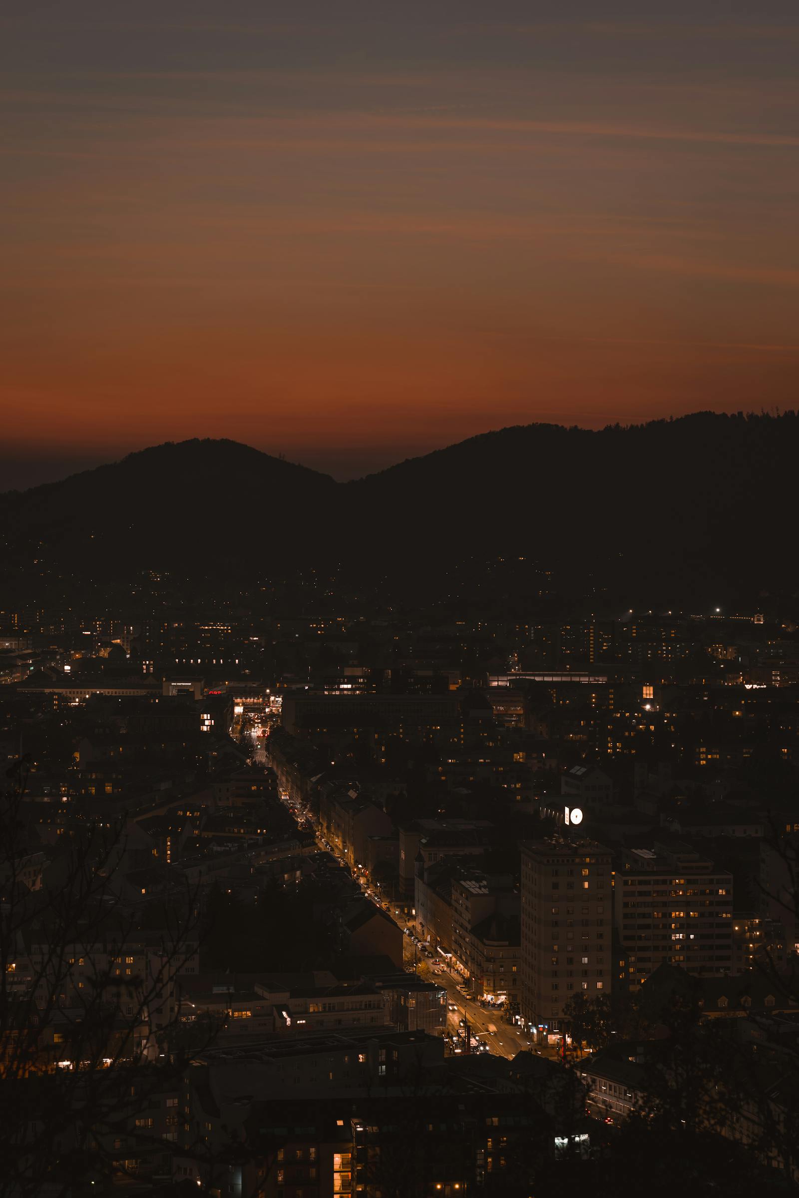 A stunning nighttime cityscape view of Graz, Austria, showcasing glowing city lights and a vibrant skyline.