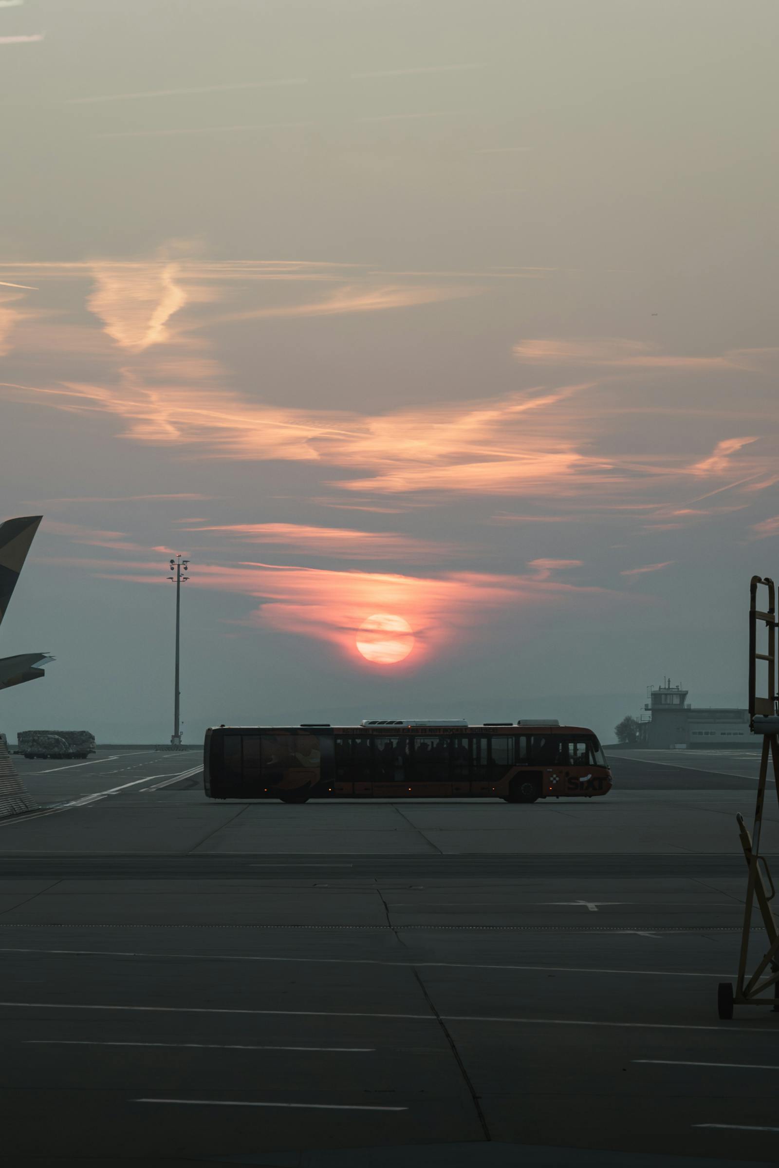 A tranquil sunset over an airport tarmac in Schwechat, Austria, with an airplane and bus visible.