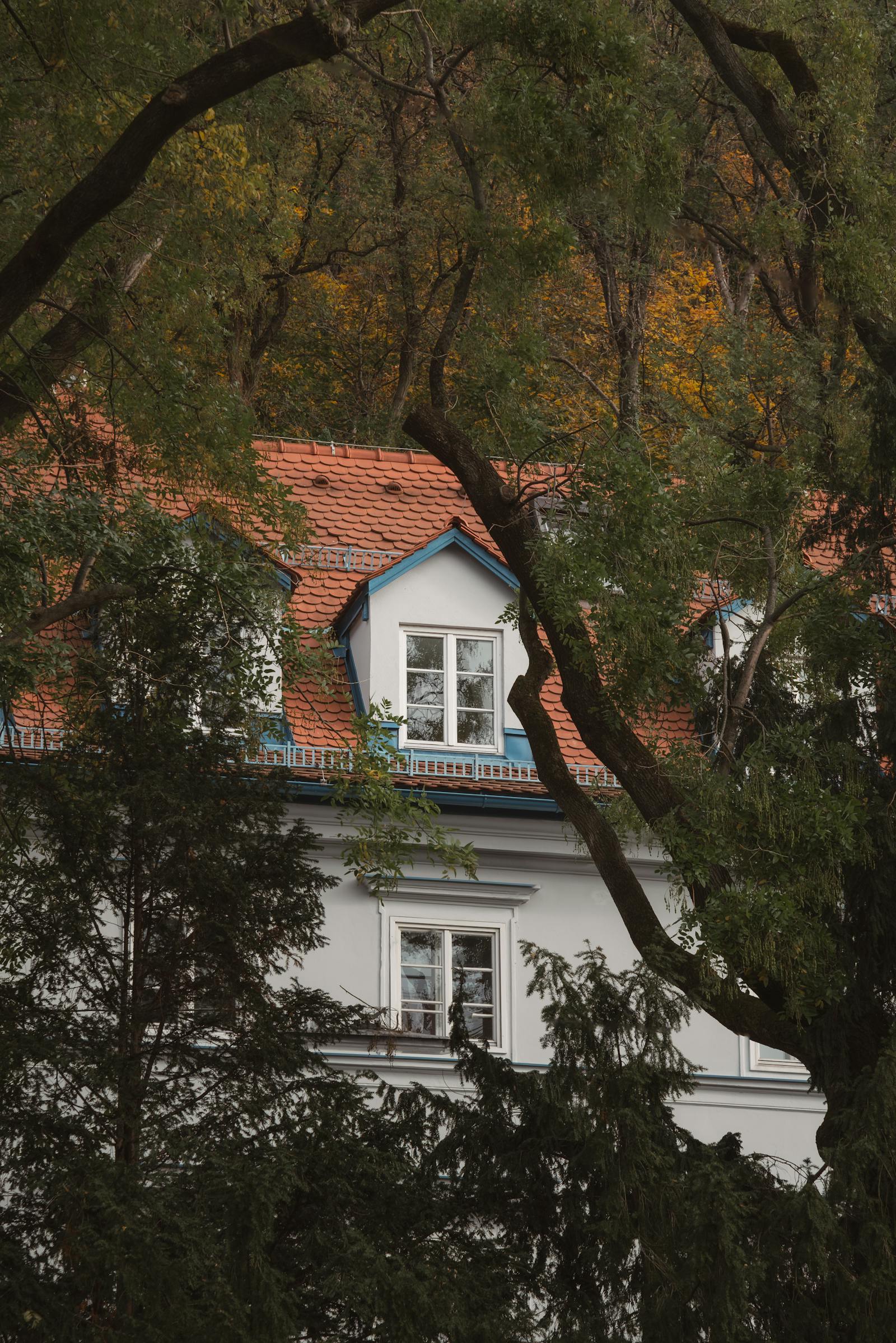 A picturesque rustic house surrounded by lush forest and vibrant autumn colors.