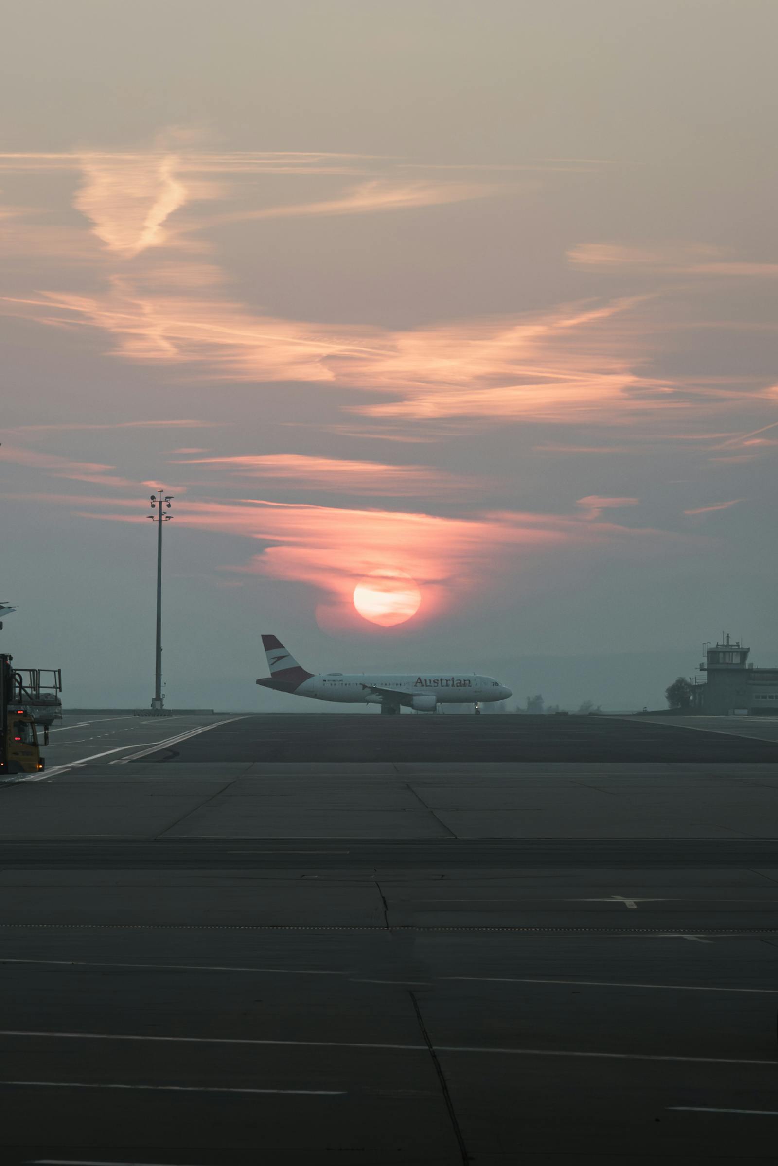 An airplane on the runway of Schwechat Airport, Austria, during a tranquil sunset.