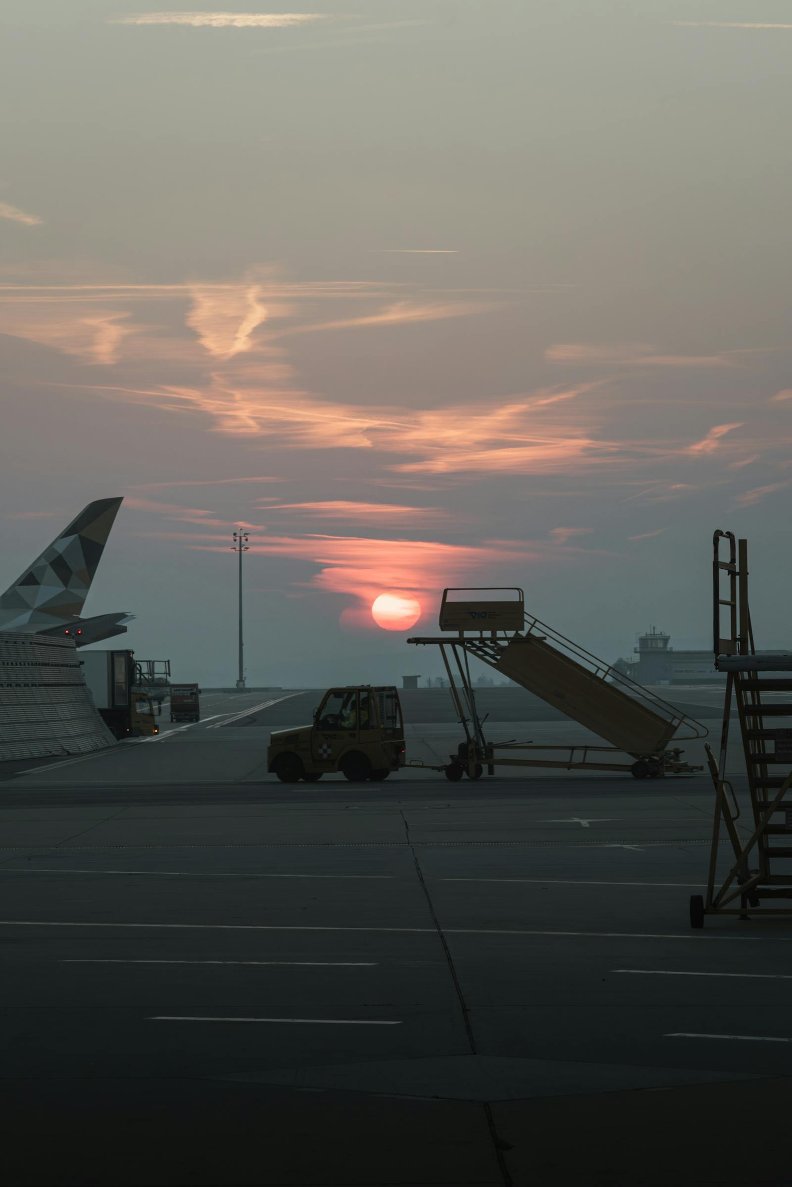 Captivating sunset over Schwechat Airport tarmac with an airplane wing and boarding stairs in view.