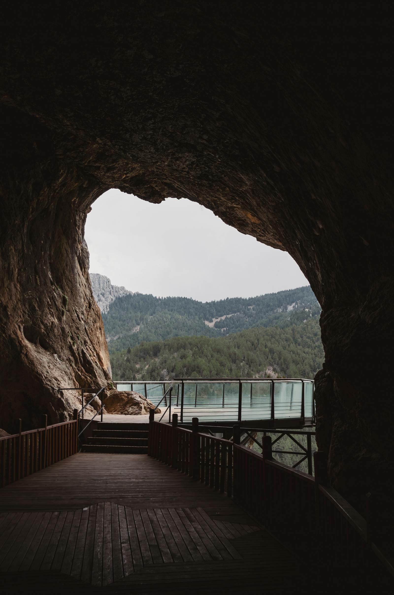 Discover the serenity of a cave entrance with a stunning view of the Taurus Mountains and tranquil lake.