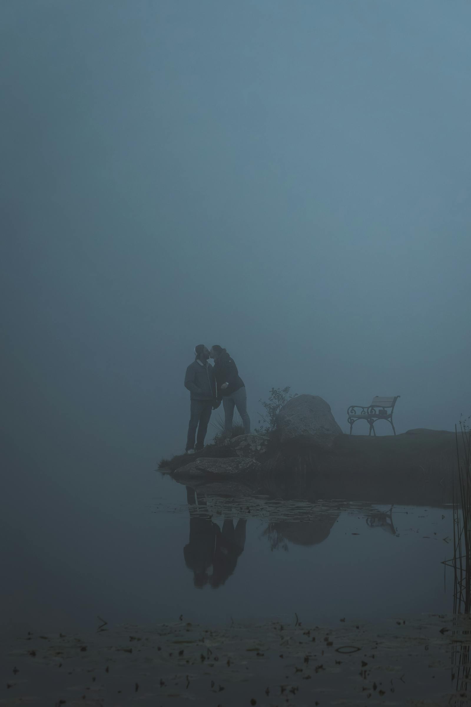 A couple embraces by a foggy lake in Styria, Austria, creating a serene and romantic atmosphere.