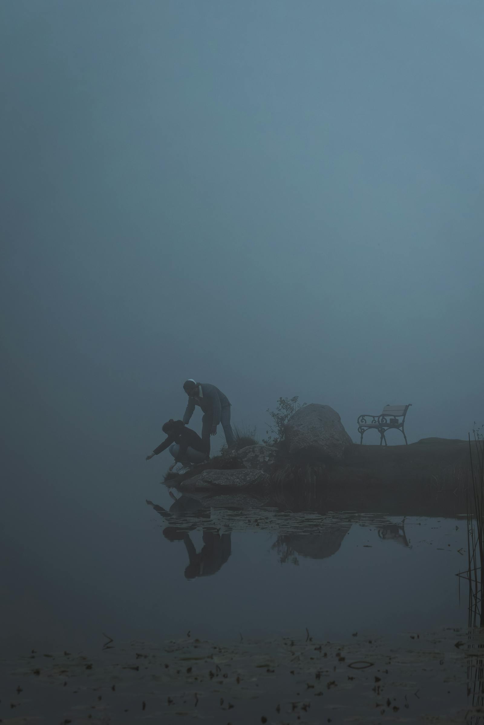 Two figures in introspection by a misty lake in Styria, Austria, embodying serenity and mystery.