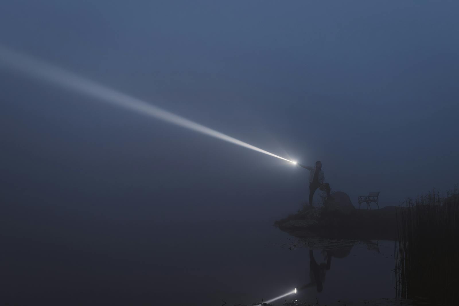 A serene lakeside exploration at night with flashlight illuminating the mist in Styria, Austria.