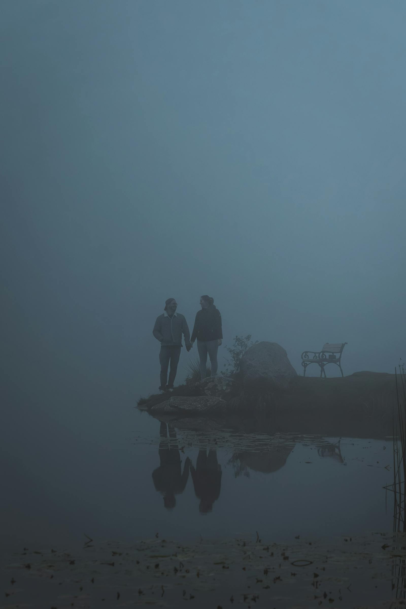 A couple stands by a foggy pond in Styria, creating a serene, mystical atmosphere.