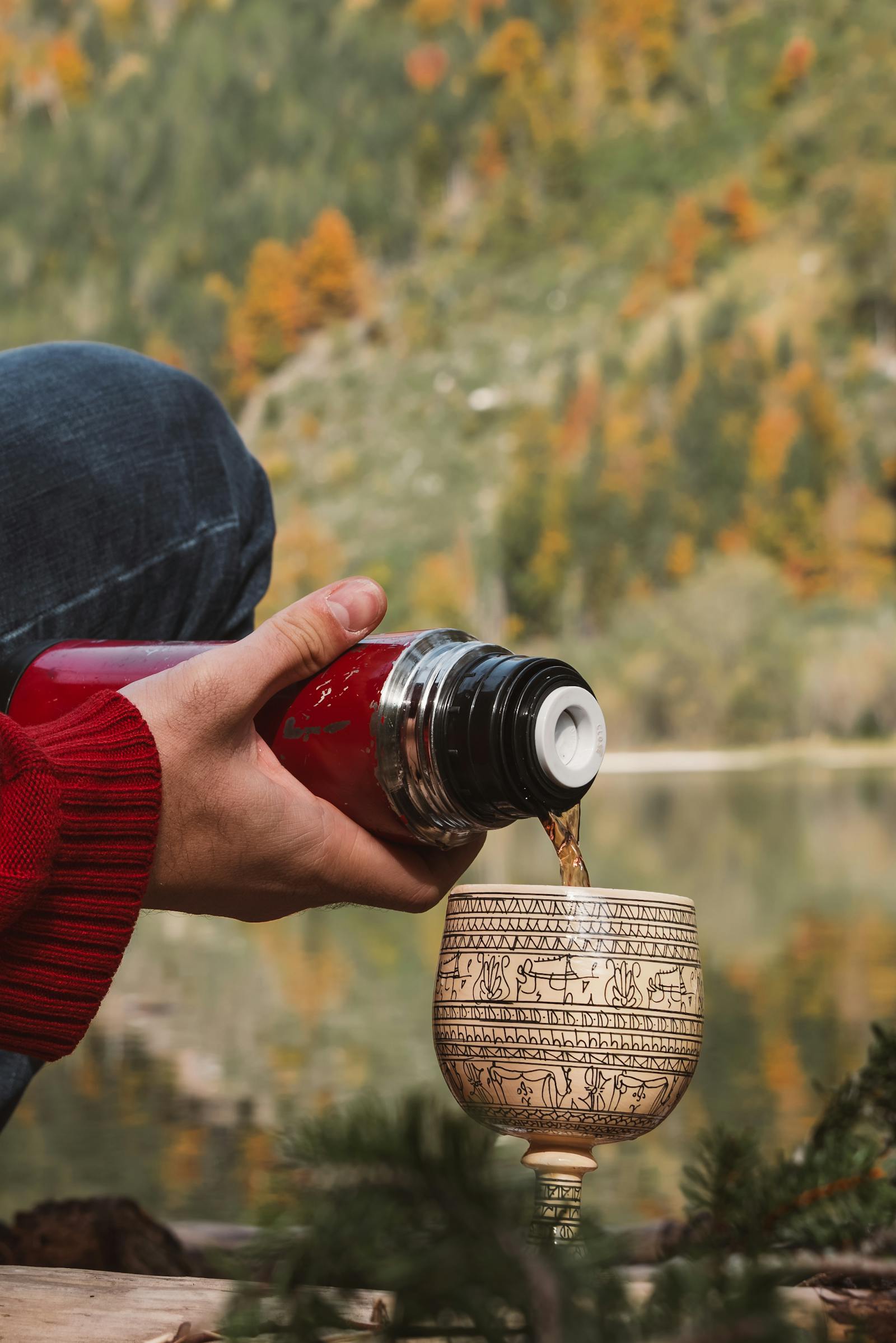 A cozy autumn scene by the lake in Styria, Austria, with a warm drink pour.