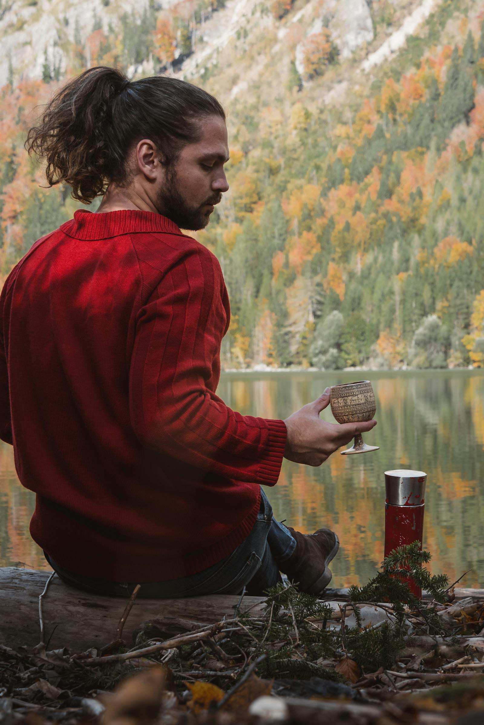 A man in a red sweater enjoys a serene moment by the lake in autumn, Austria.