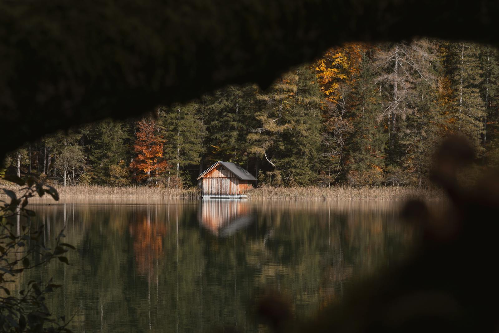 A tranquil autumn scene of a cabin by a lake in the alpine forests of Eisenerz, Austria.