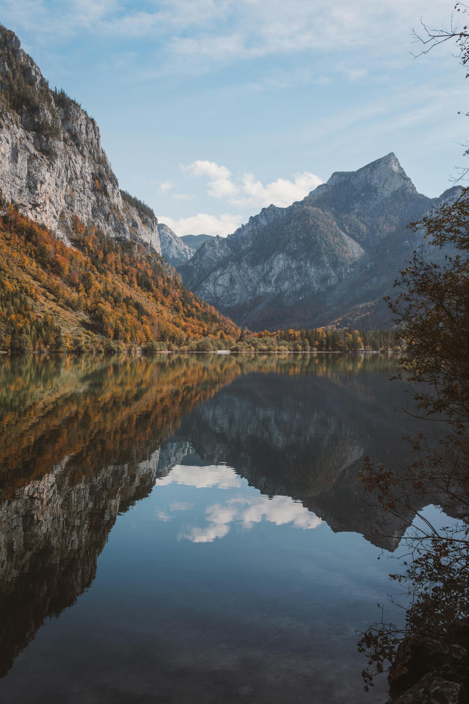 A tranquil autumn landscape with mountains reflected in a calm lake in Eisenerz, Austria.