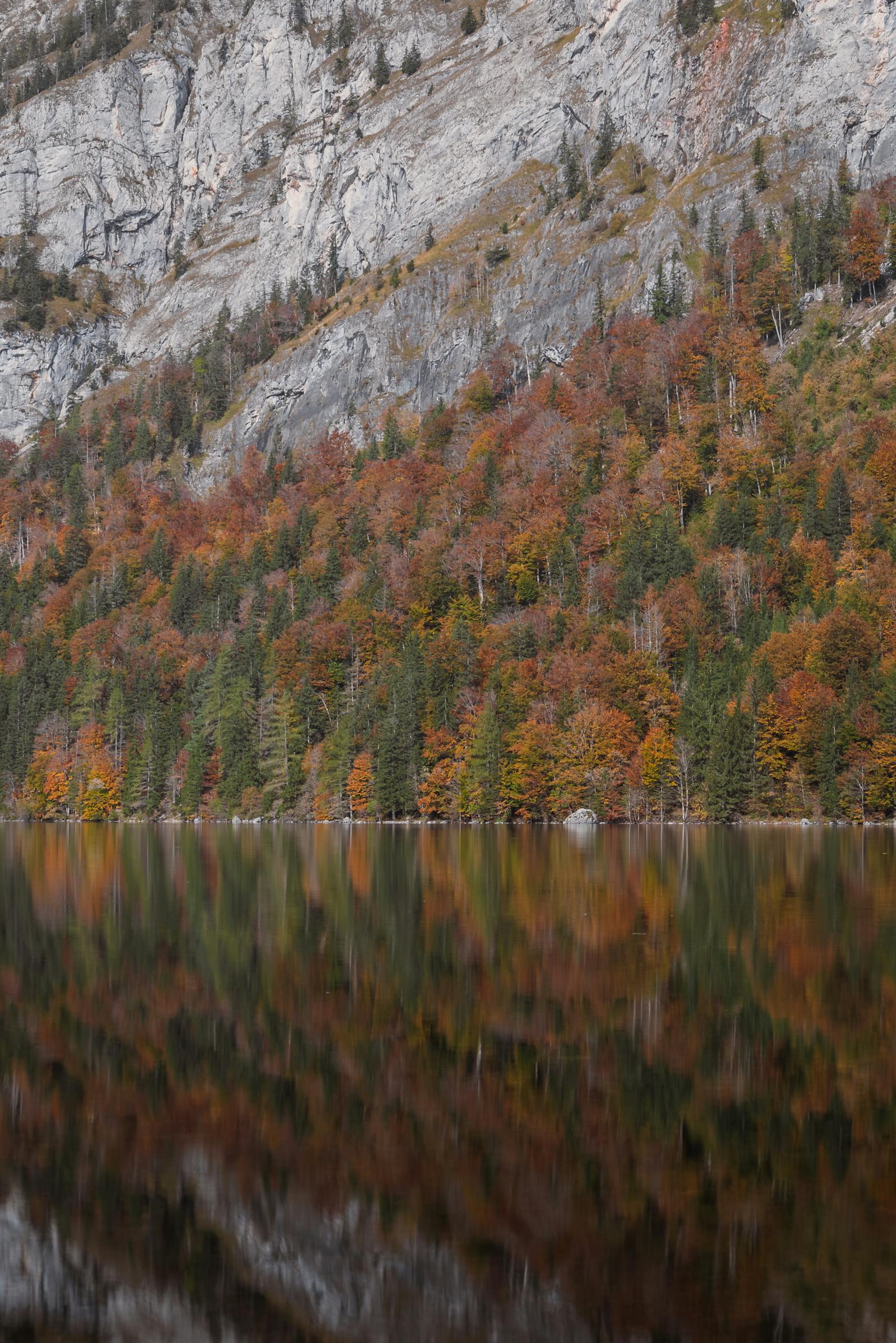 Peaceful autumn scene with vibrant trees reflecting in a lake in Eisenerz, Austria.