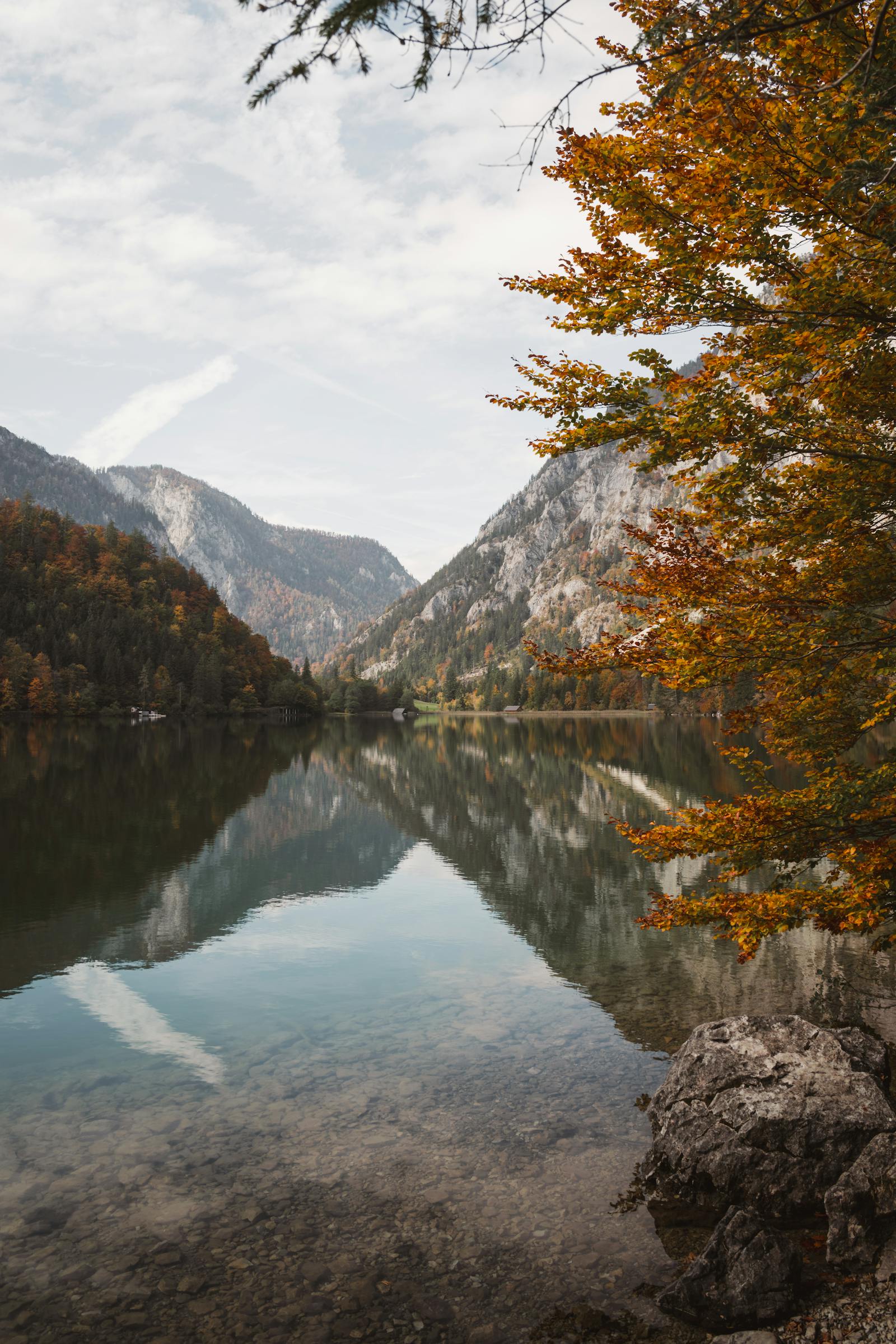 Tranquil alpine lake with autumn foliage reflecting the mountains. Perfect for serene and peaceful scenery.