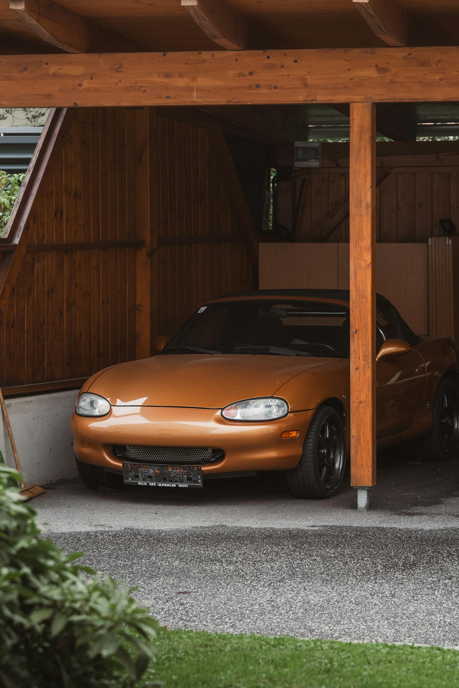 A classic Mazda parked in a wooden garage, evoking nostalgic retro vibes.