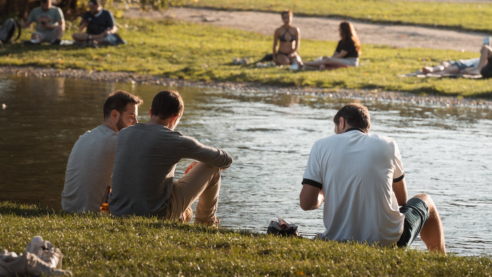 A group of friends enjoying a peaceful afternoon by the river in a park.