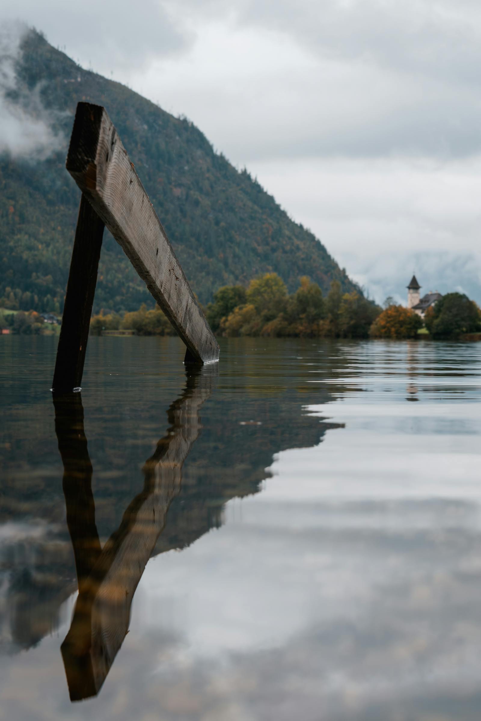 Peaceful alpine lake scene with wooden structure reflecting in calm waters.