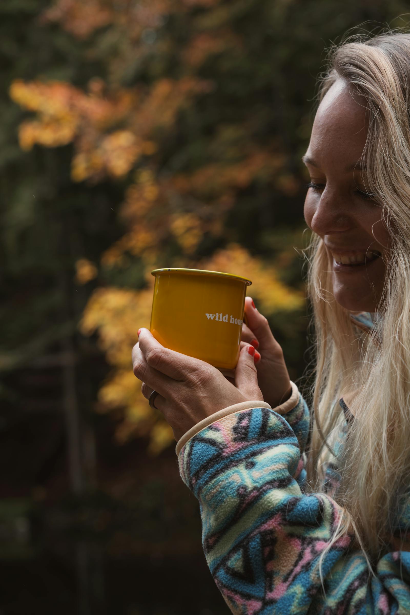 Woman enjoying a warm drink outdoors during autumn, capturing the essence of tranquility and joy.