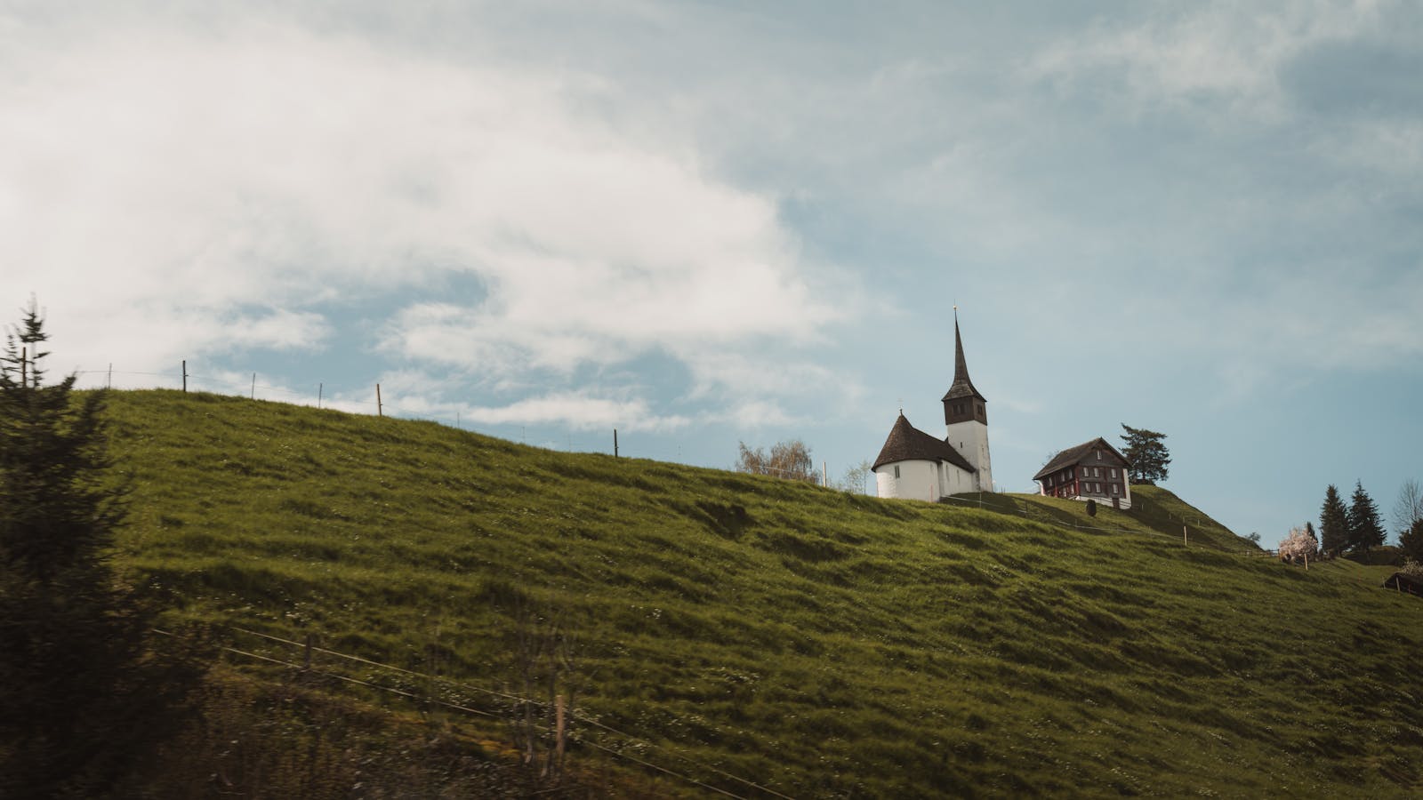 Serene view of a historic church on a lush hillside under a clear blue sky.