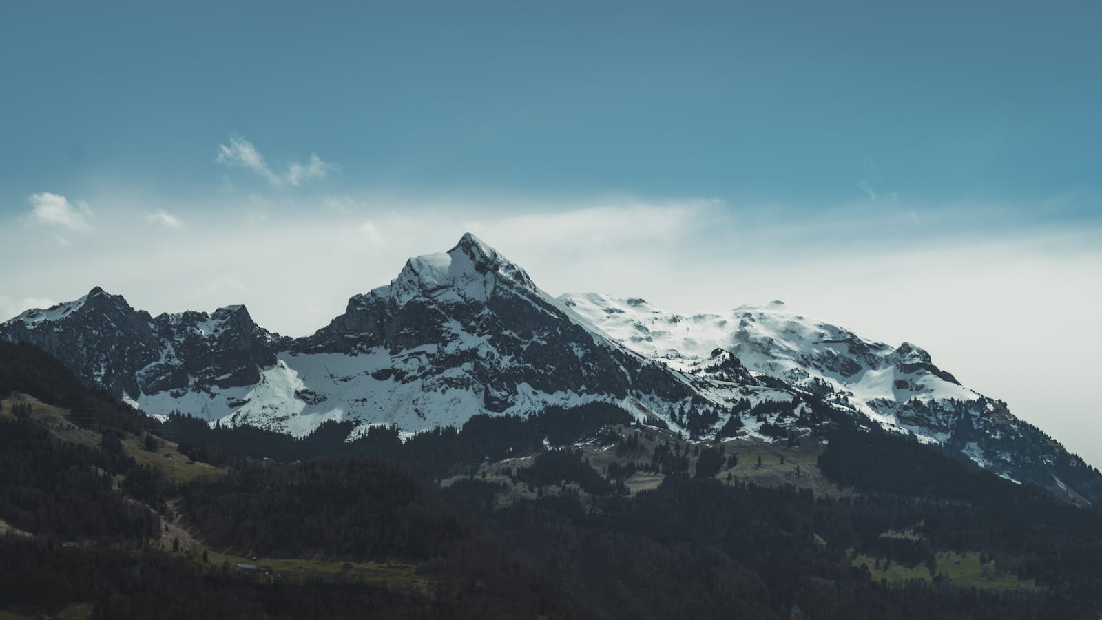 Breathtaking view of snow-covered mountain peaks under a clear blue sky, epitomizing natural beauty.