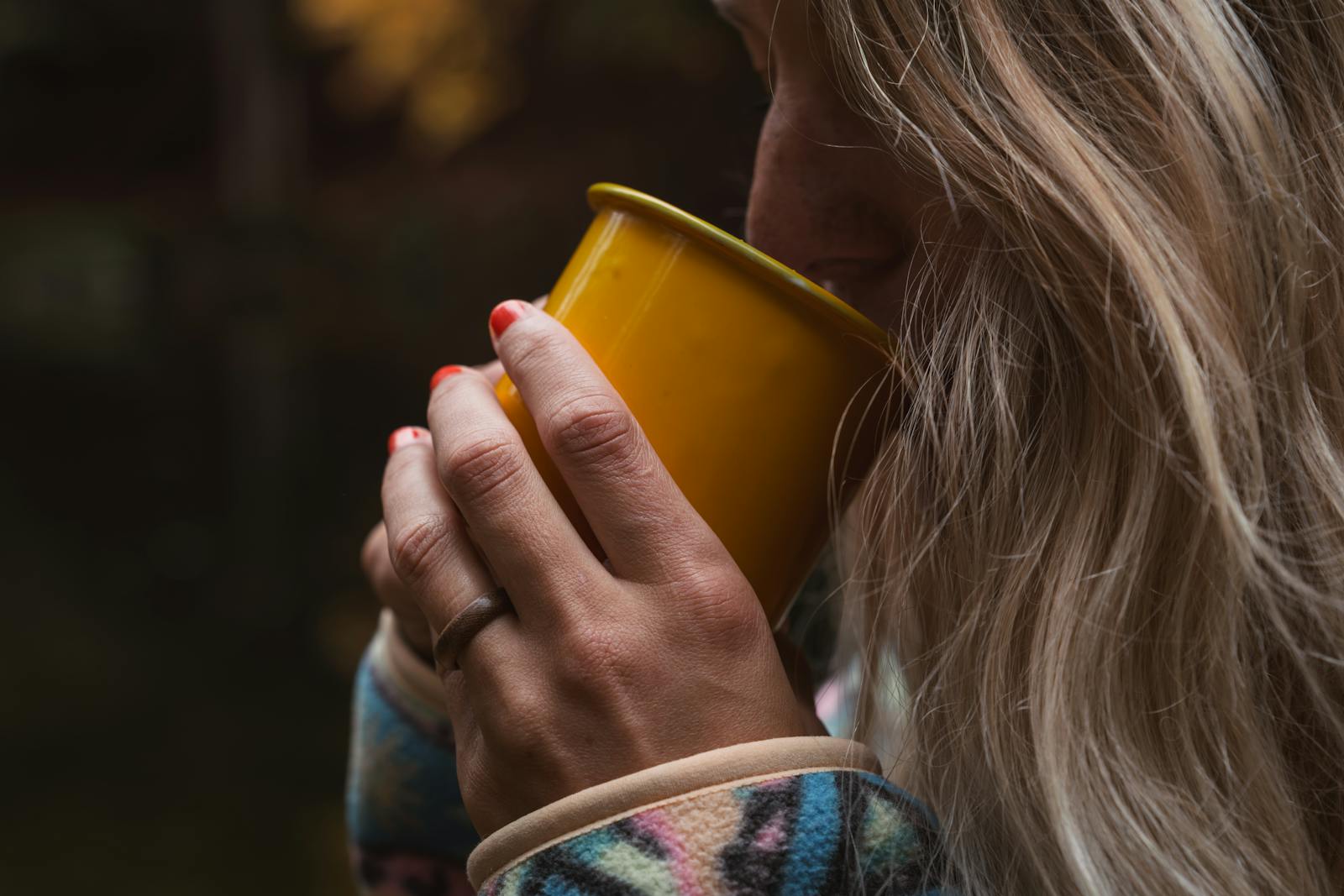 A tranquil moment captured with a person enjoying a warm drink in an autumn forest setting.