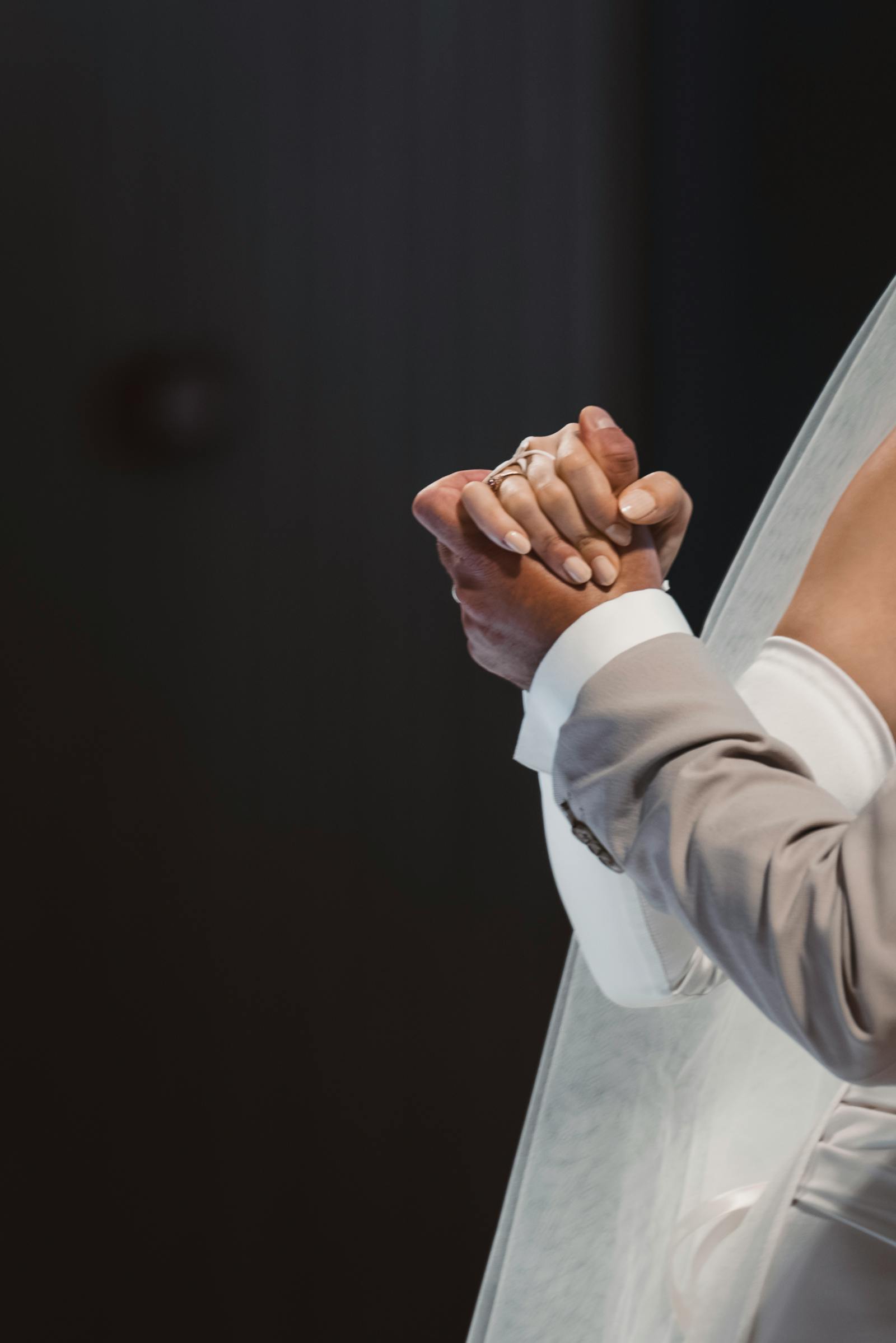 Close-up of a bride and groom tenderly holding hands, symbolizing timeless love and unity.