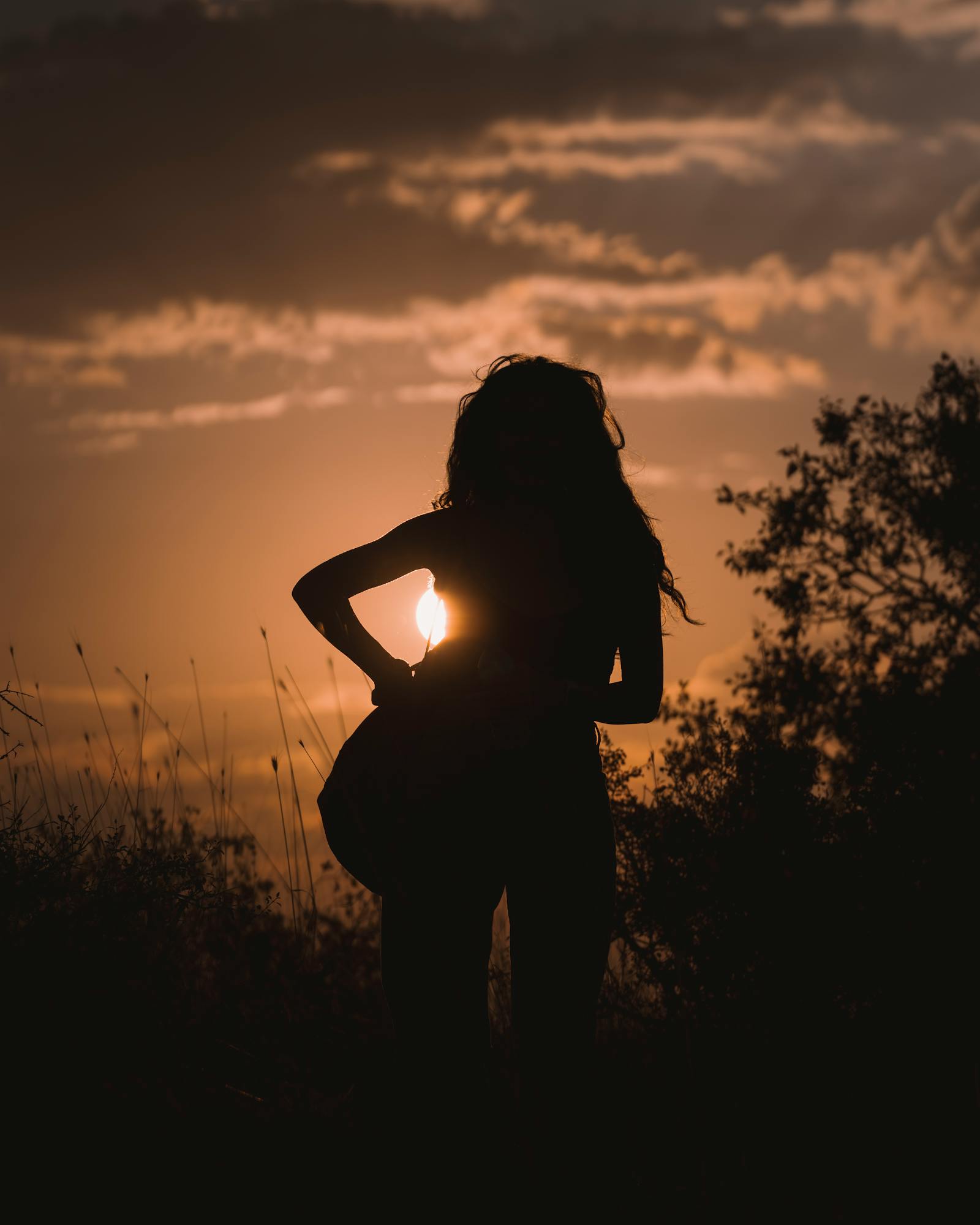 A serene silhouette of a woman playing guitar against a dramatic Ankara sunset.