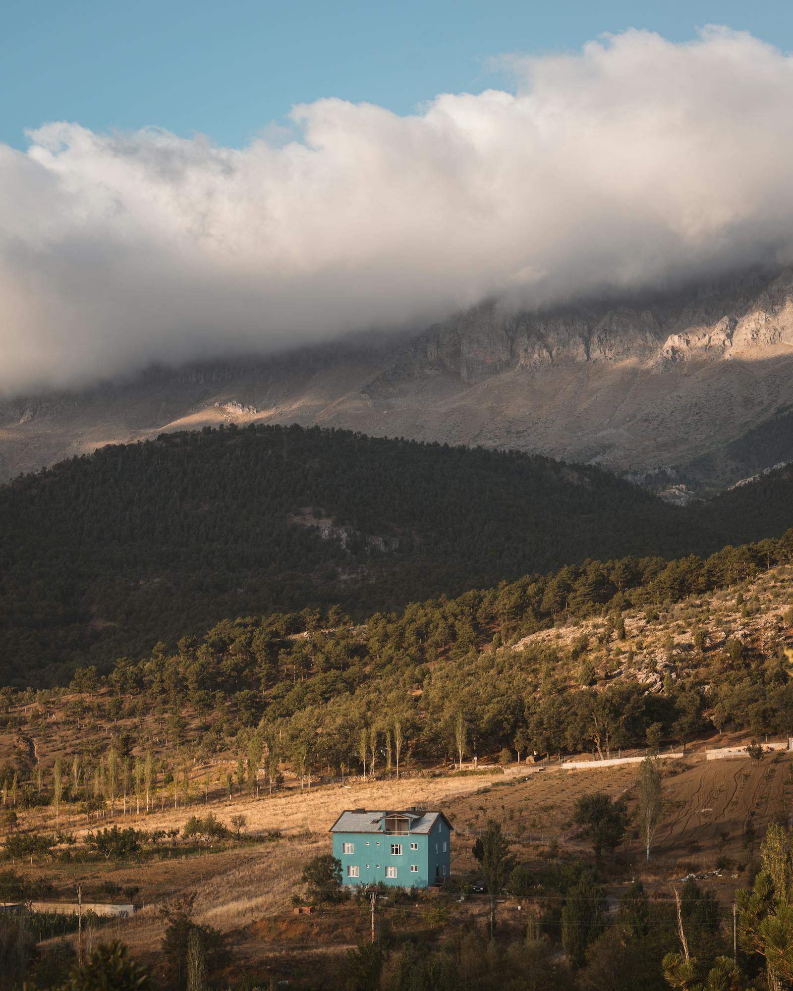 A tranquil scene of a blue house amidst misty mountains in Seydişehir, Turkey.