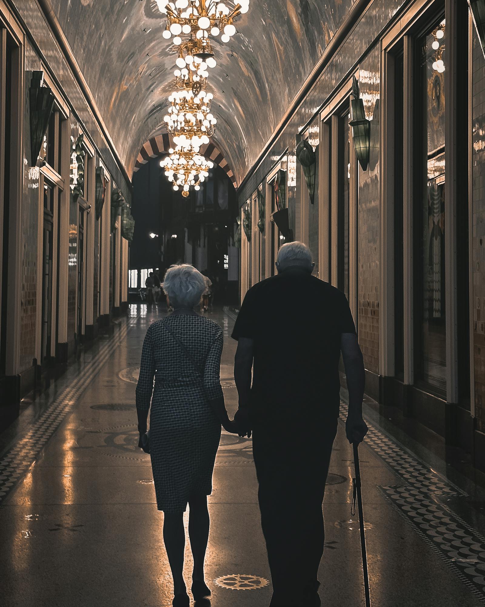 Silhouetted elderly couple walking through a lit hallway in Amsterdam.