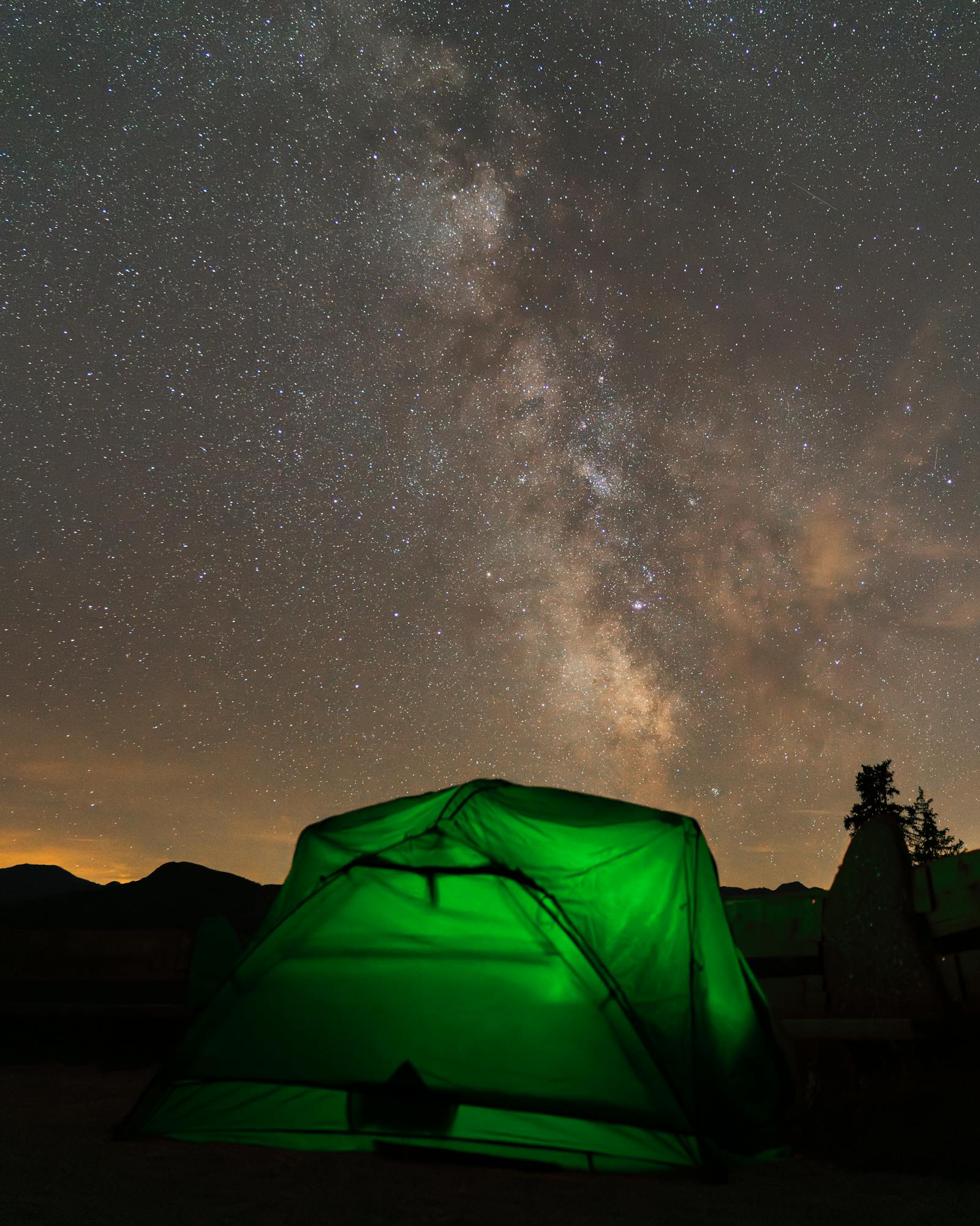 A glowing tent under the starry sky and Milky Way at a campsite in Innsbruck, Austria.