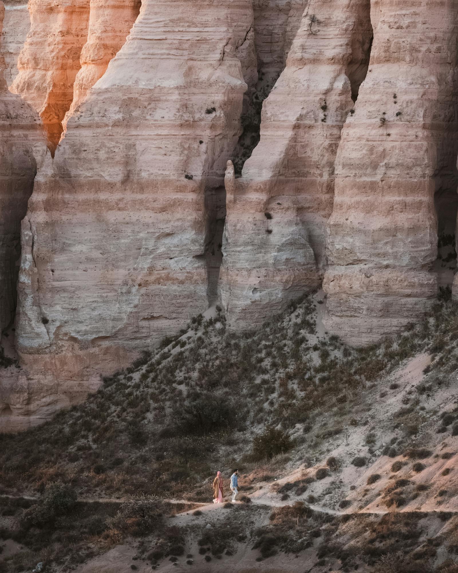 A couple explores the breathtaking sandstone cliffs in Göreme, Türkiye during golden hour.