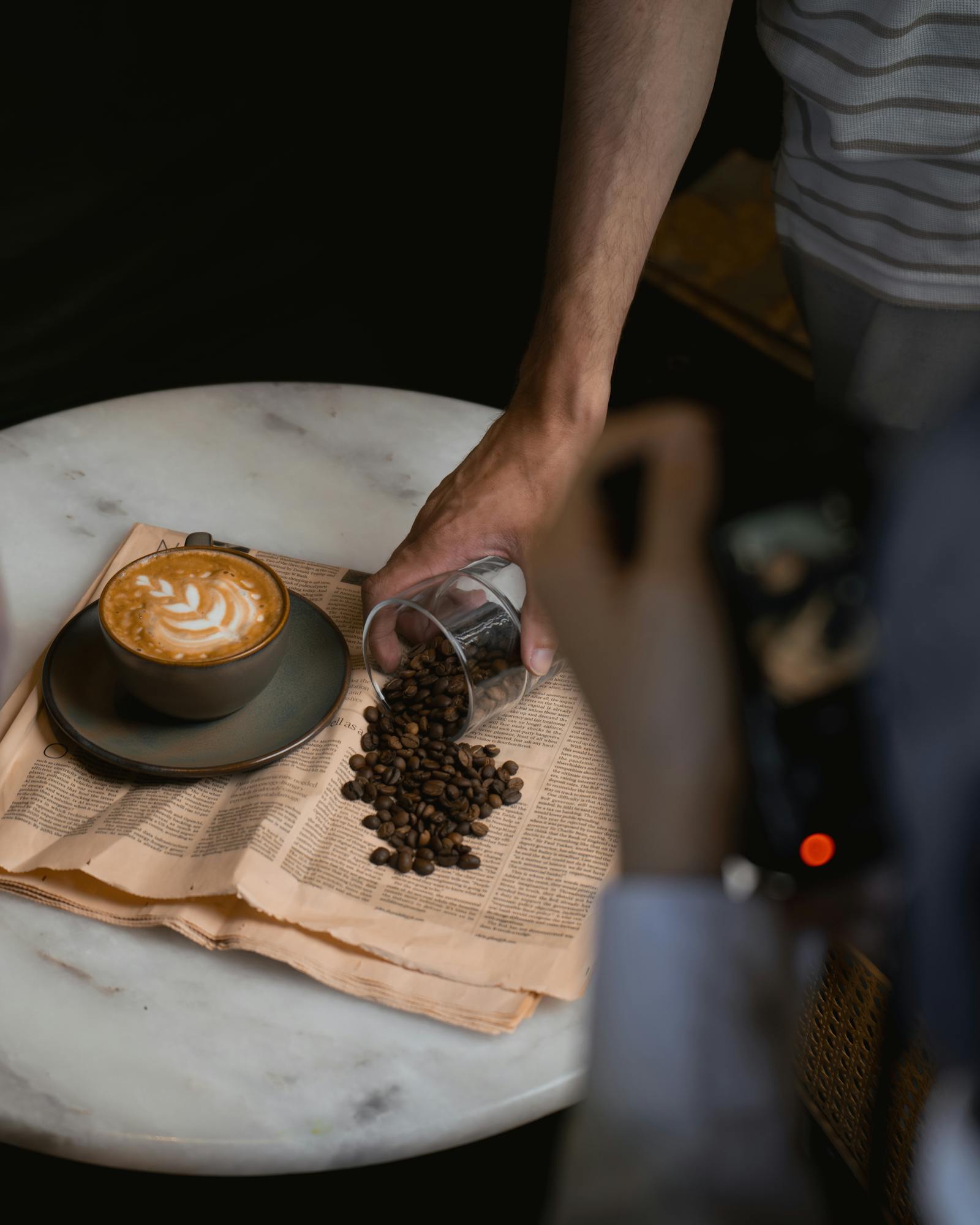 Artistic coffee scene with cappuccino, coffee beans, and newspaper at a cafe in Ankara.