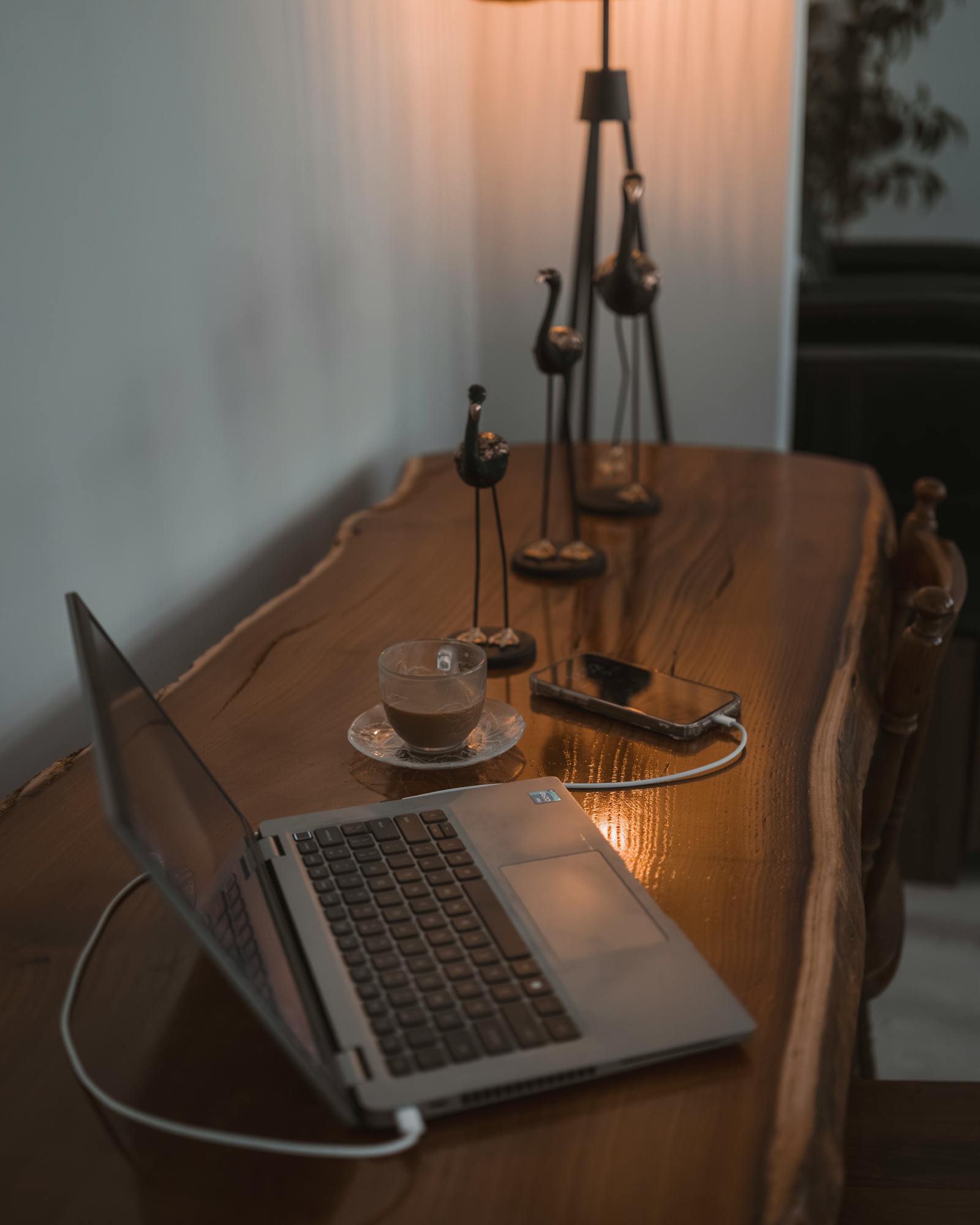 Warmly lit home office setting with a laptop, coffee, and soft lighting, perfect for productivity and relaxation.