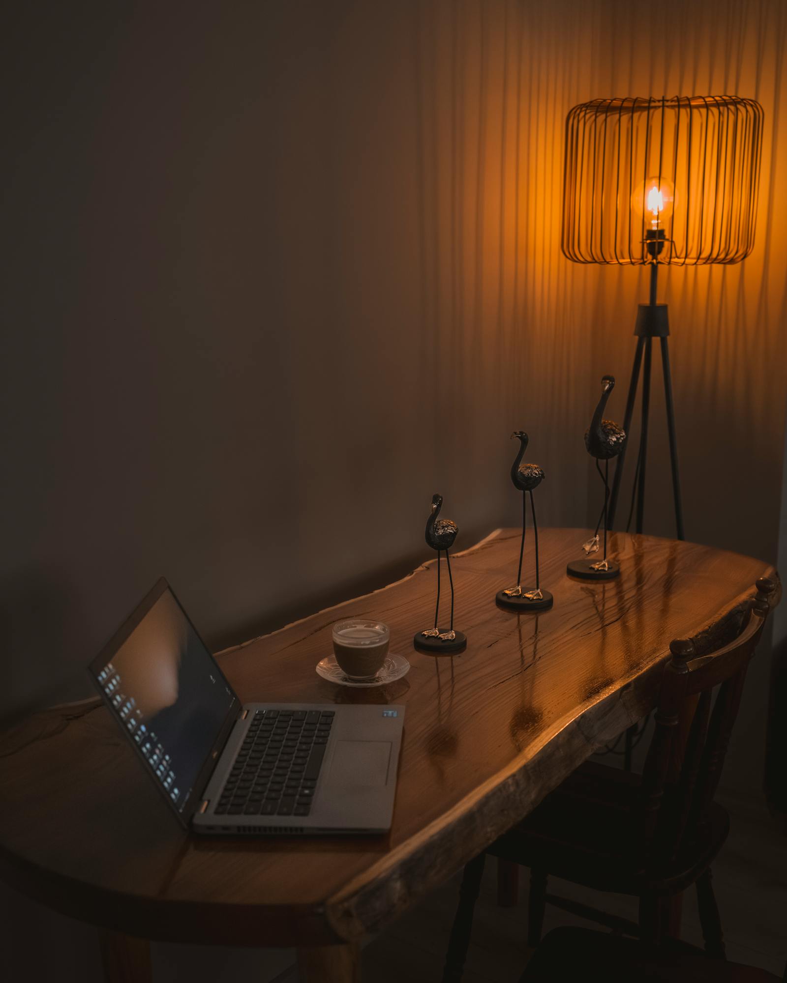 A warm-lit home office desk setup with a laptop and coffee, perfect for productivity.