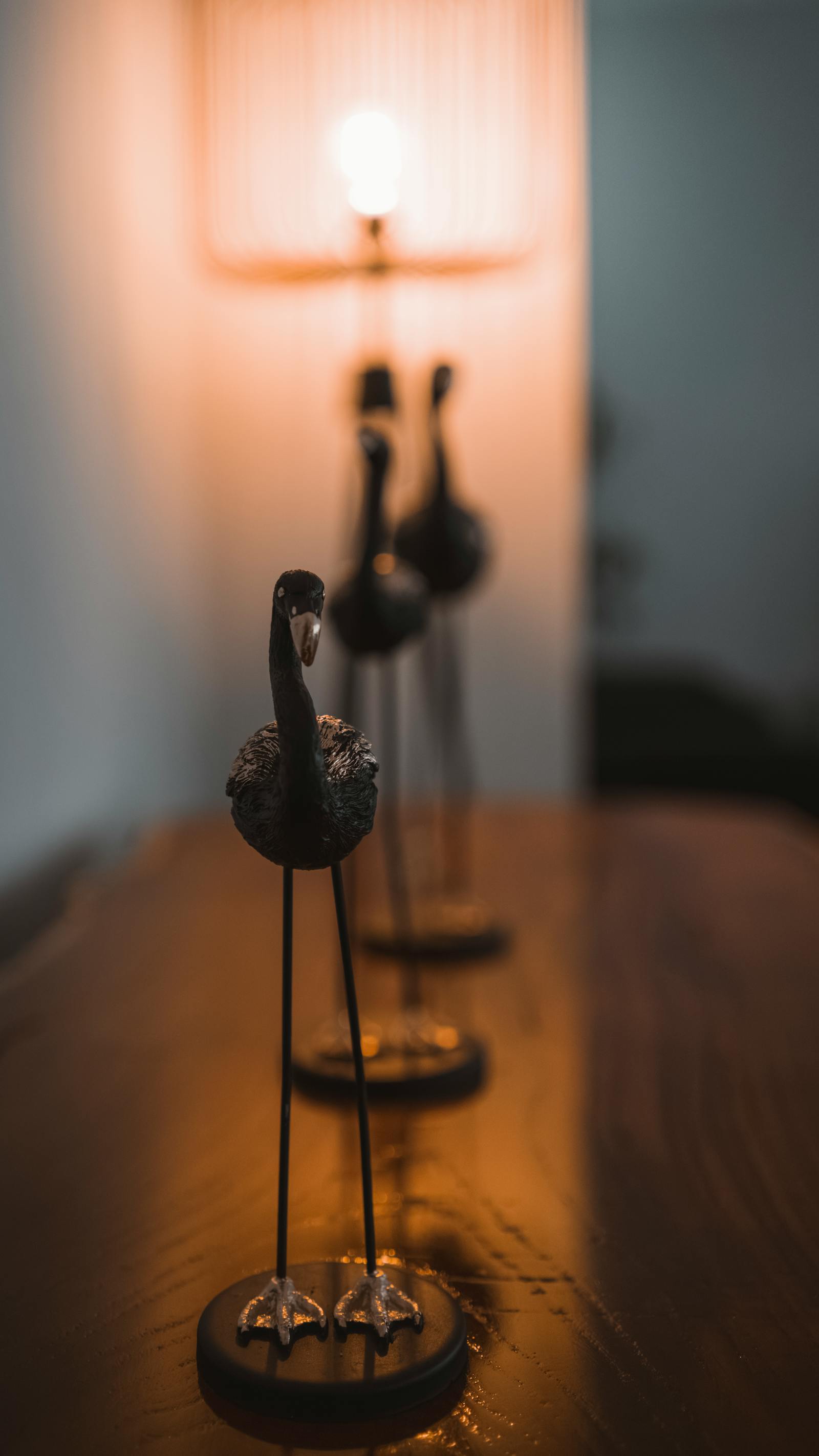 Artistic setup of bird sculptures in warm lighting on a wooden table.