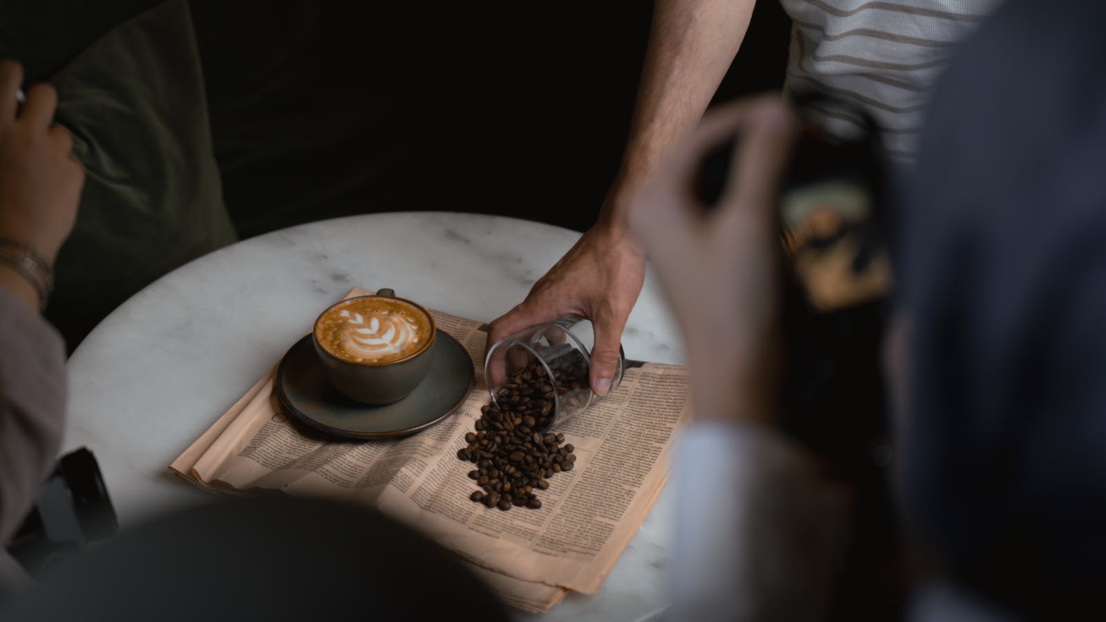 Elegant latte art with coffee beans and a newspaper in a cozy Ankara cafe setting.