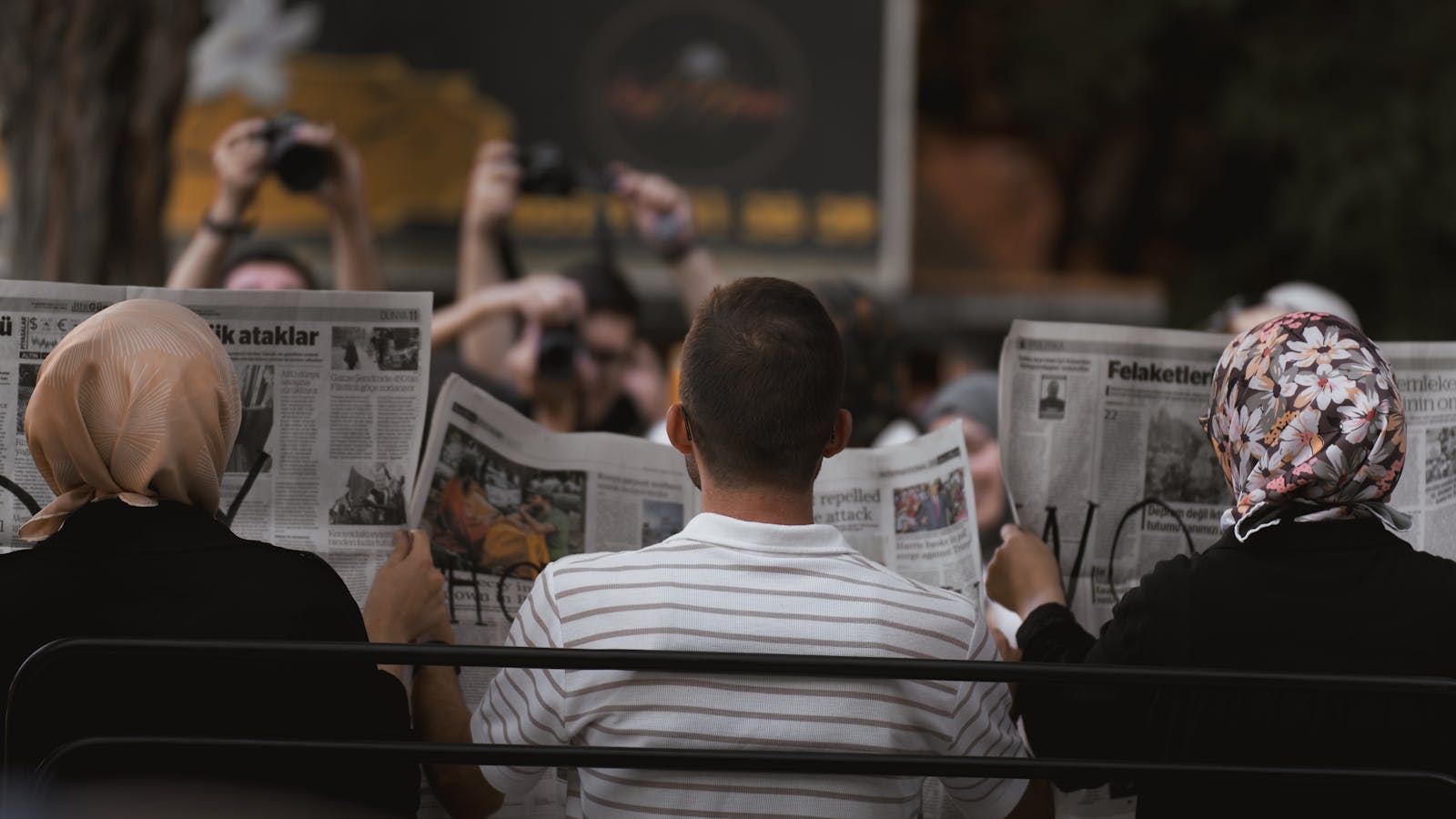 A candid moment of people reading newspapers on a bench in Ankara park.