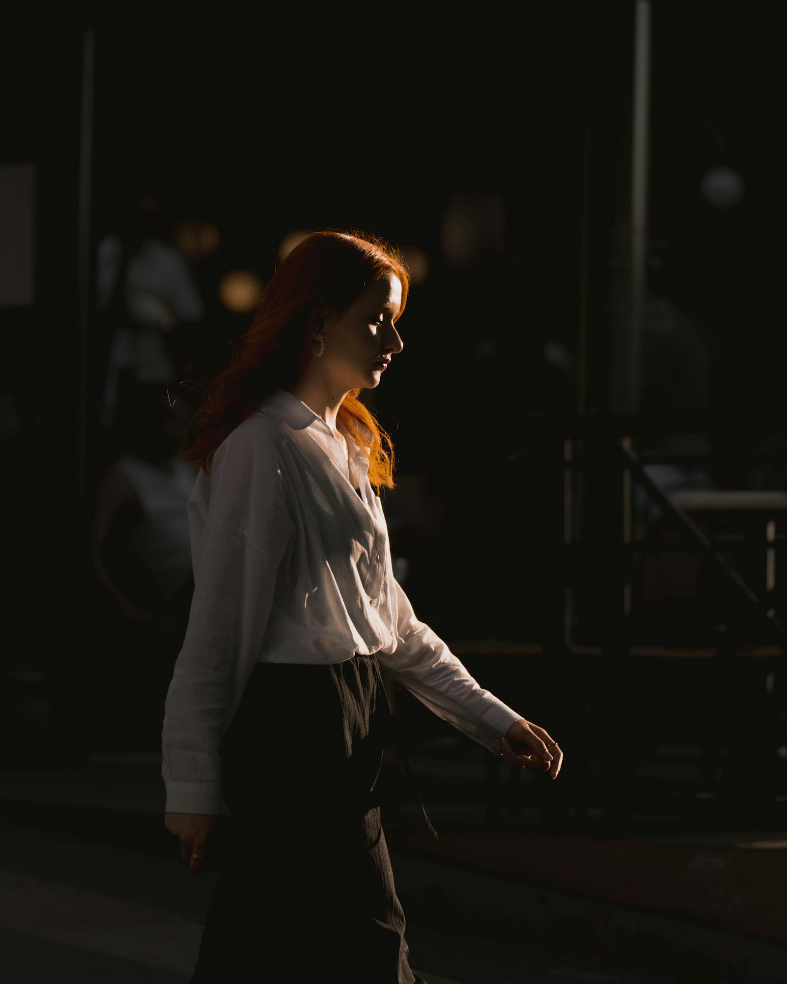 Side profile of a woman with red hair walking through shaded streets in Ankara.