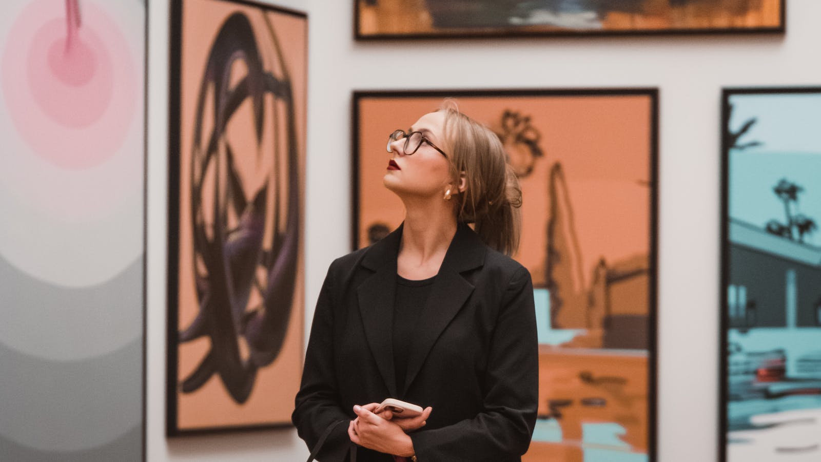 A woman in an art gallery thoughtfully observing modern artwork, reflecting creativity.