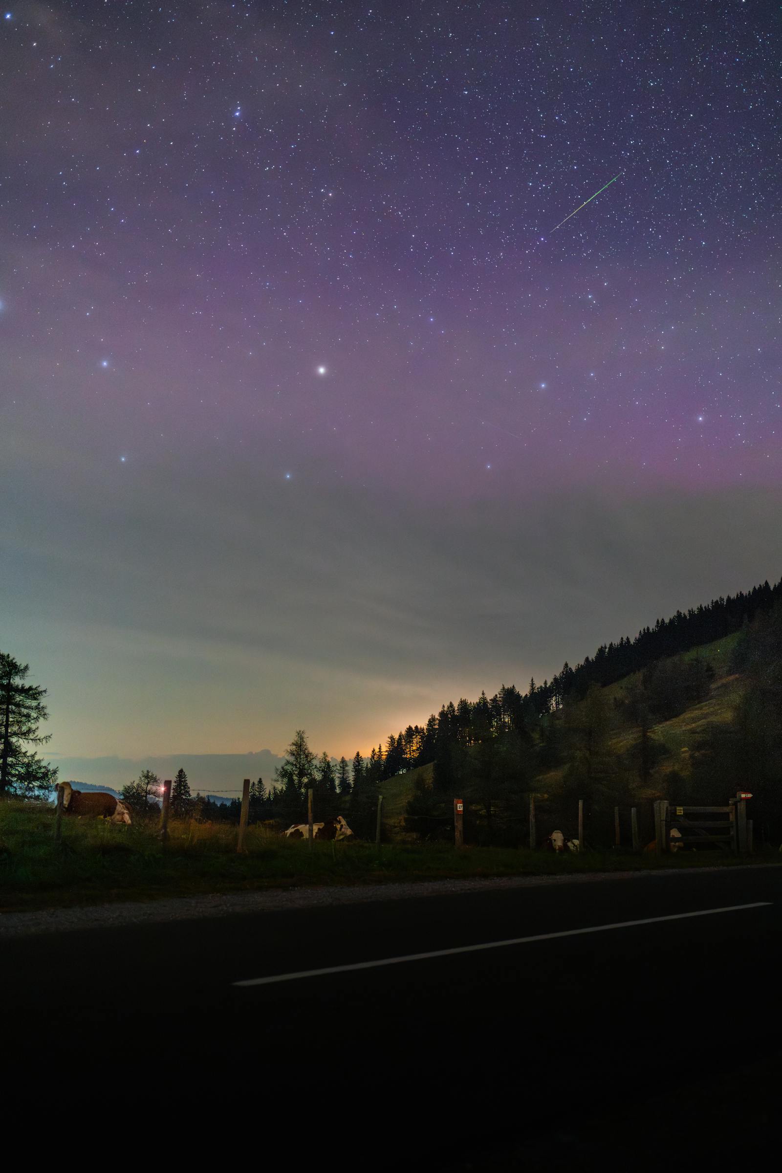 Breathtaking night sky with shooting star over Graz hillside, perfect for stargazing.