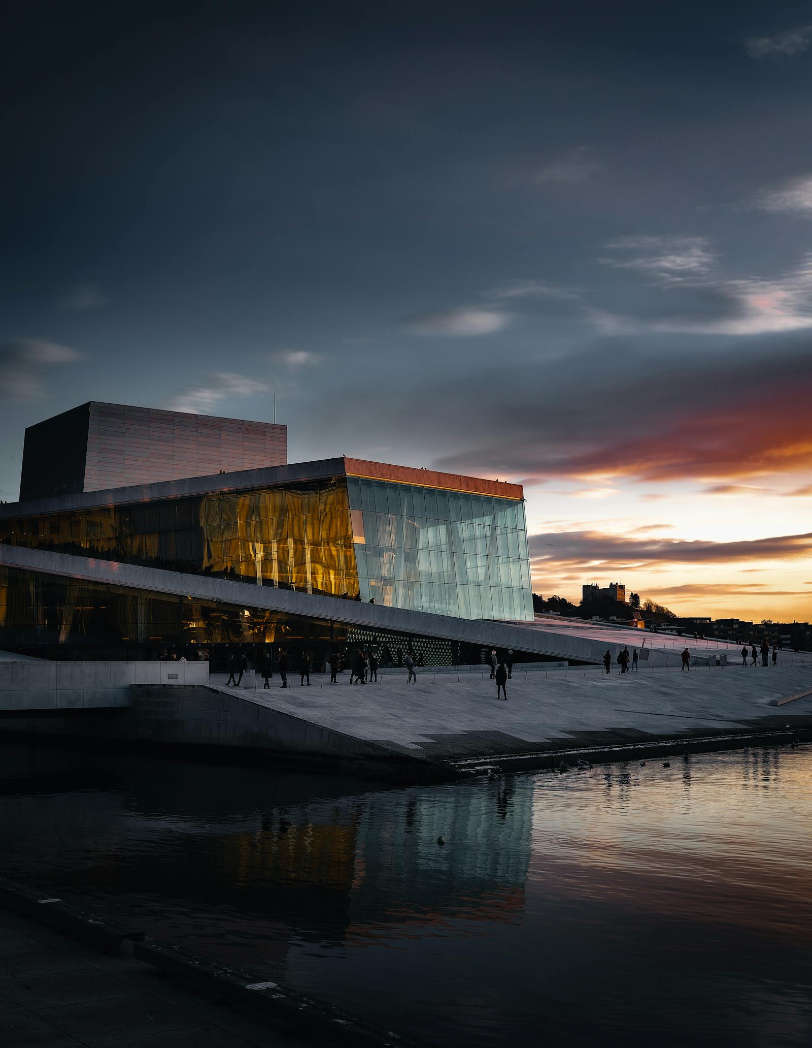 Stunning view of Oslo Opera House with sunset reflecting on the water.