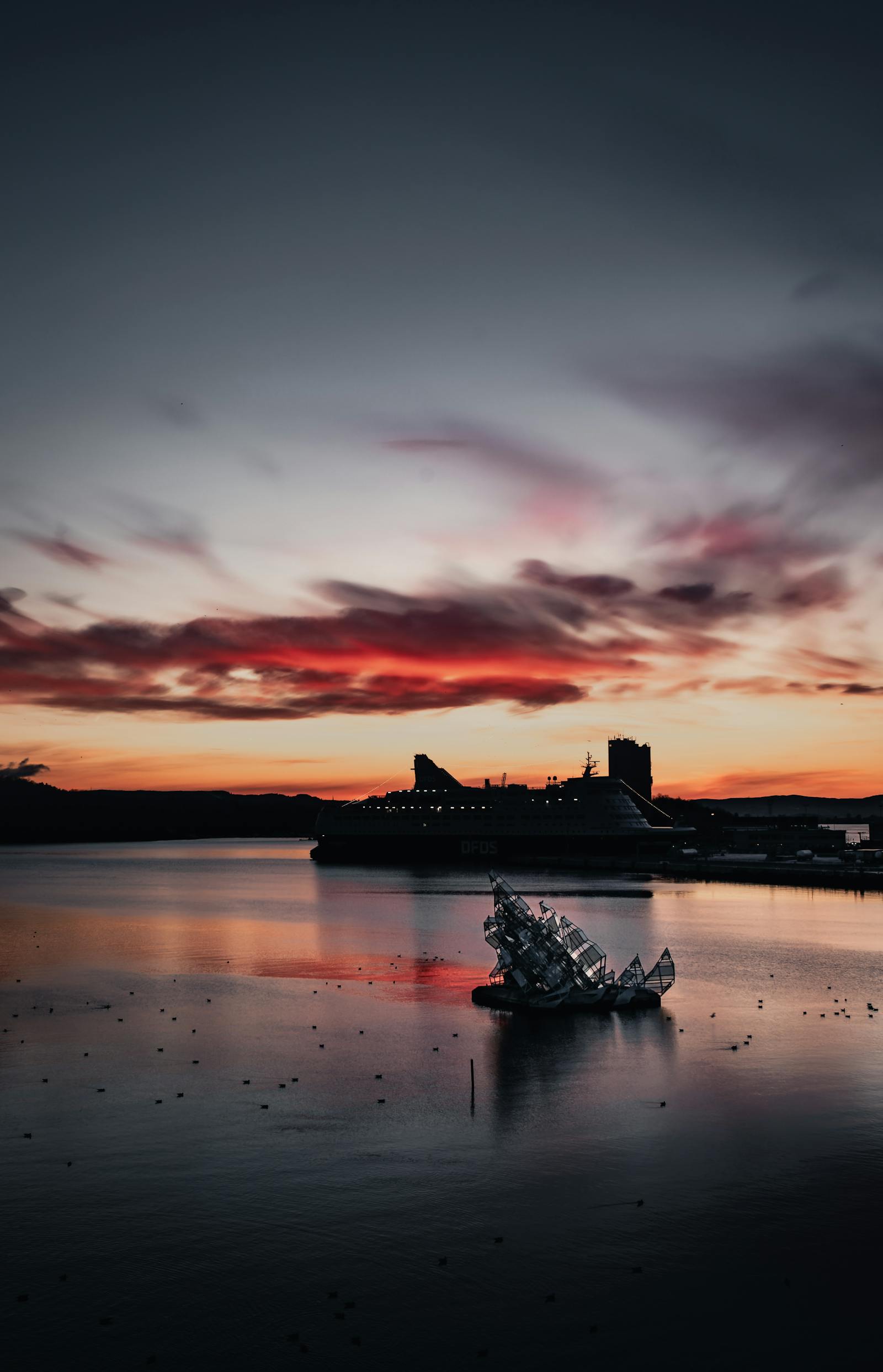 Captivating sunset view of Oslo Fjord featuring a cruise ship and vibrant sky hues.