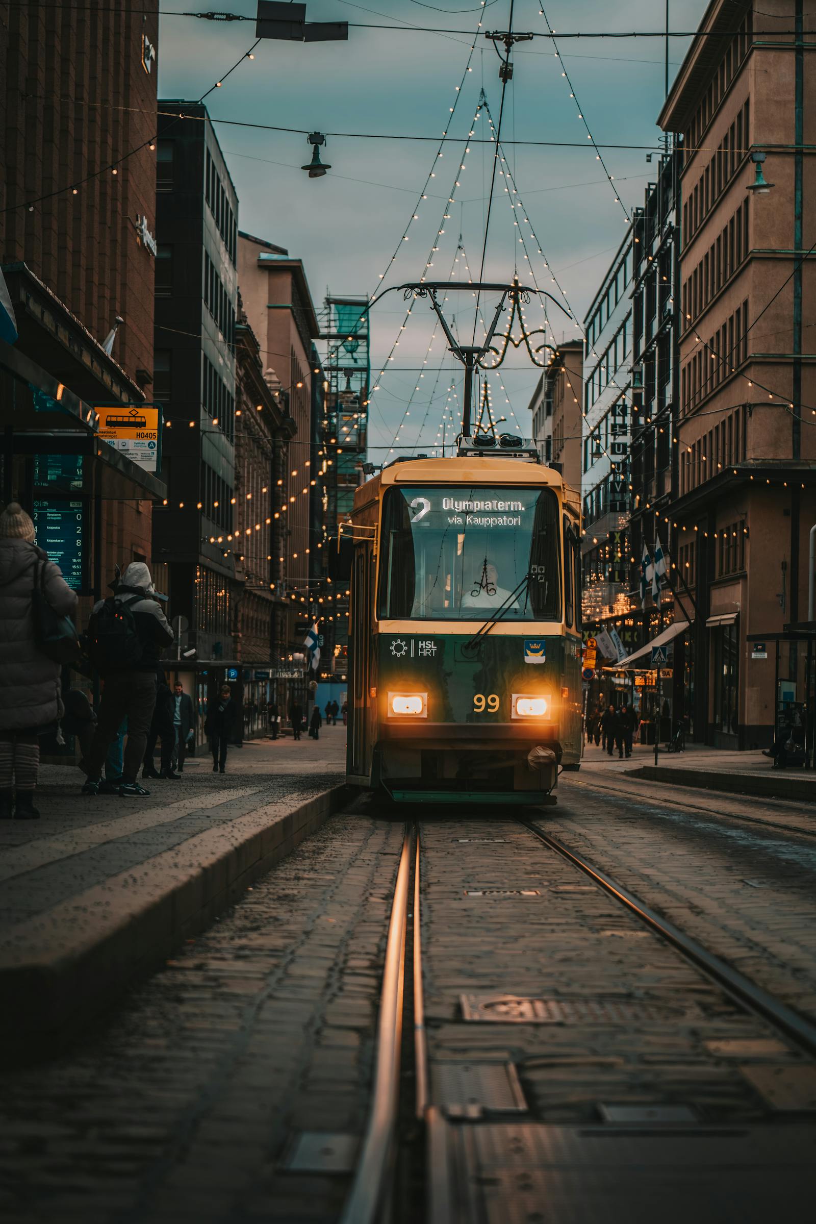 Capture of a tram under festive lights in Helsinki, showcasing urban life and public transport.