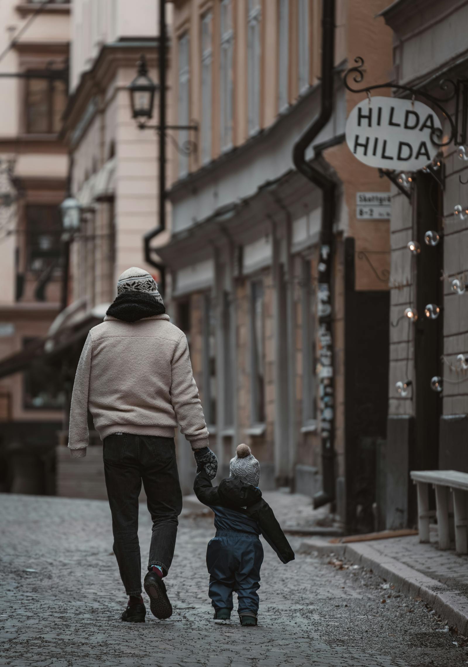 A mother and child walk hand in hand down a charming alley in Stockholm, Sweden.