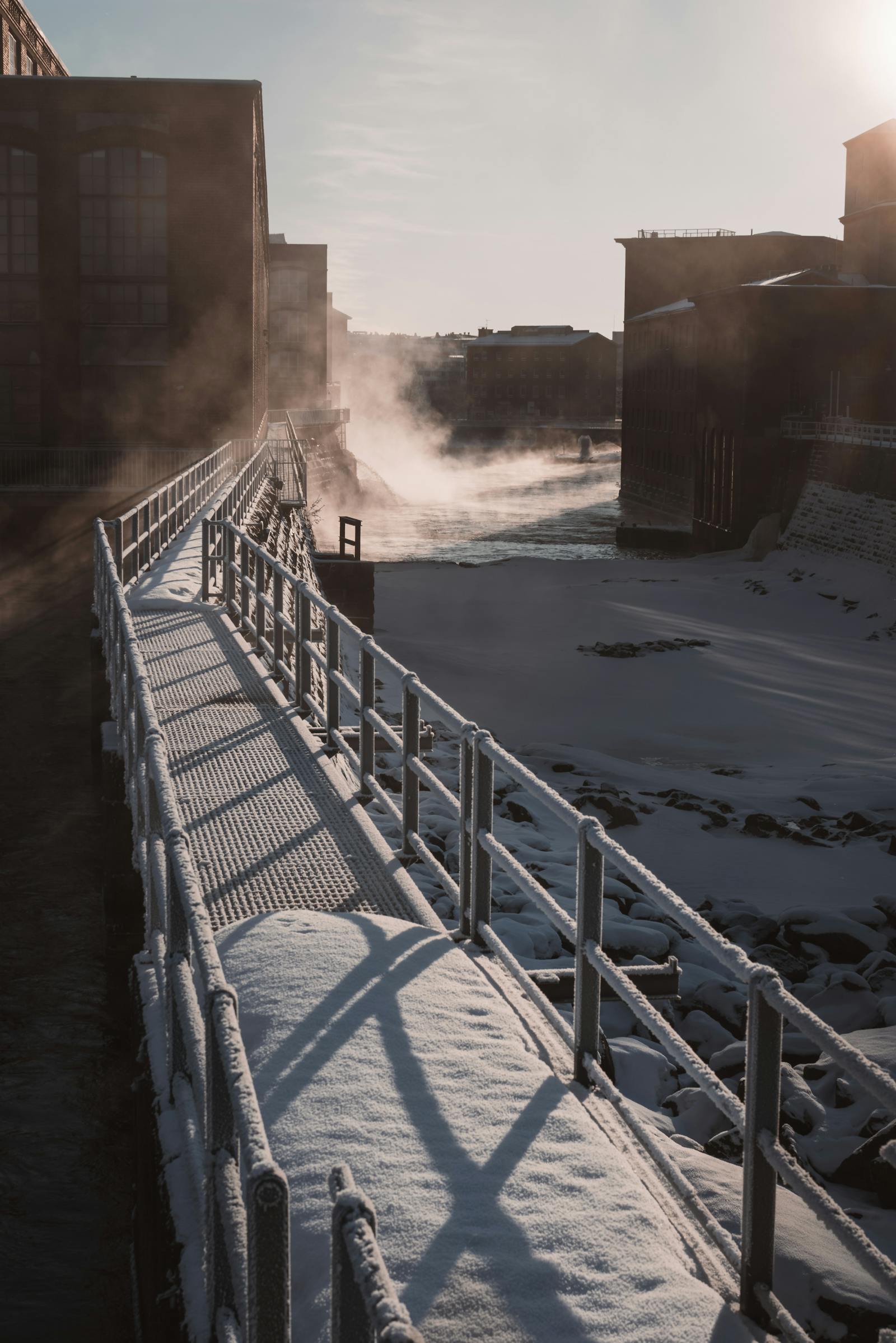 Snow-covered walkway in Stockholm's industrial area during a serene winter morning.