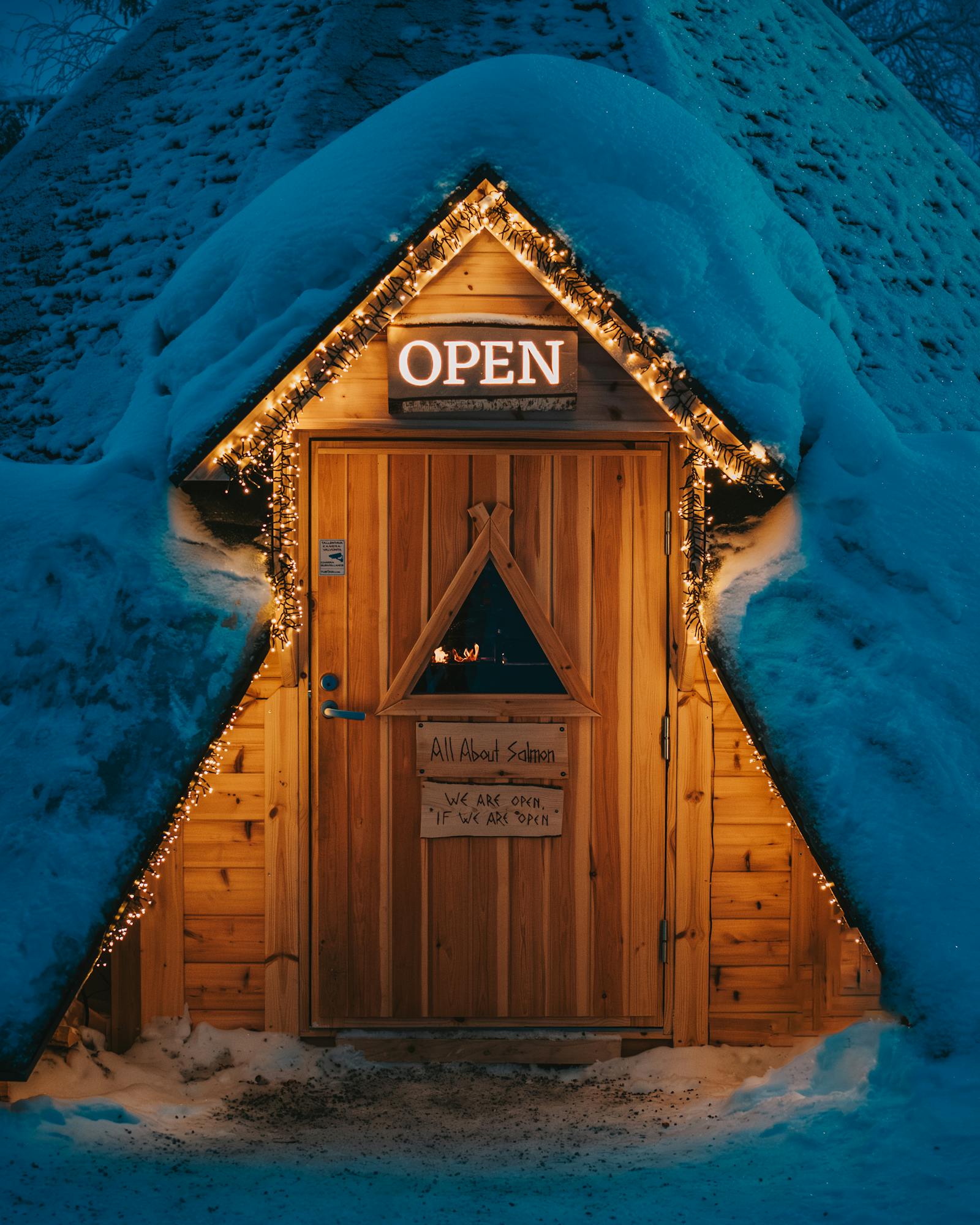 Warmly lit wooden entrance surrounded by snow, capturing a winter night in Rovaniemi, Finland.