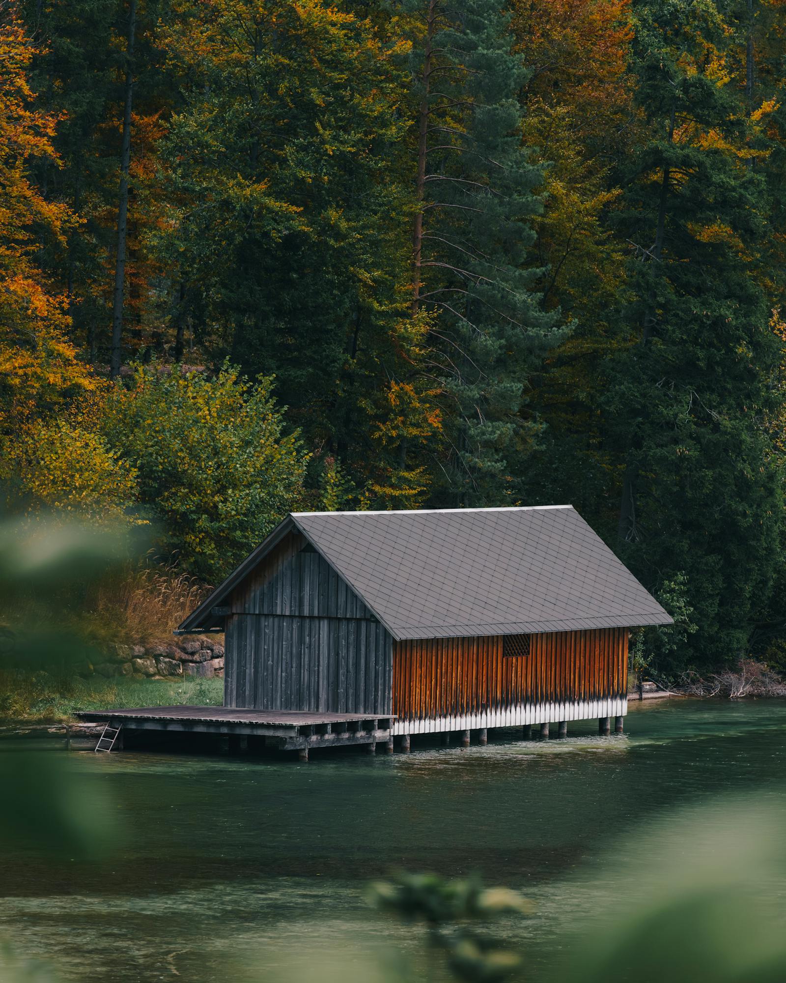 A charming boathouse surrounded by autumn trees on the lakeshore in Eisenerz, Austria.